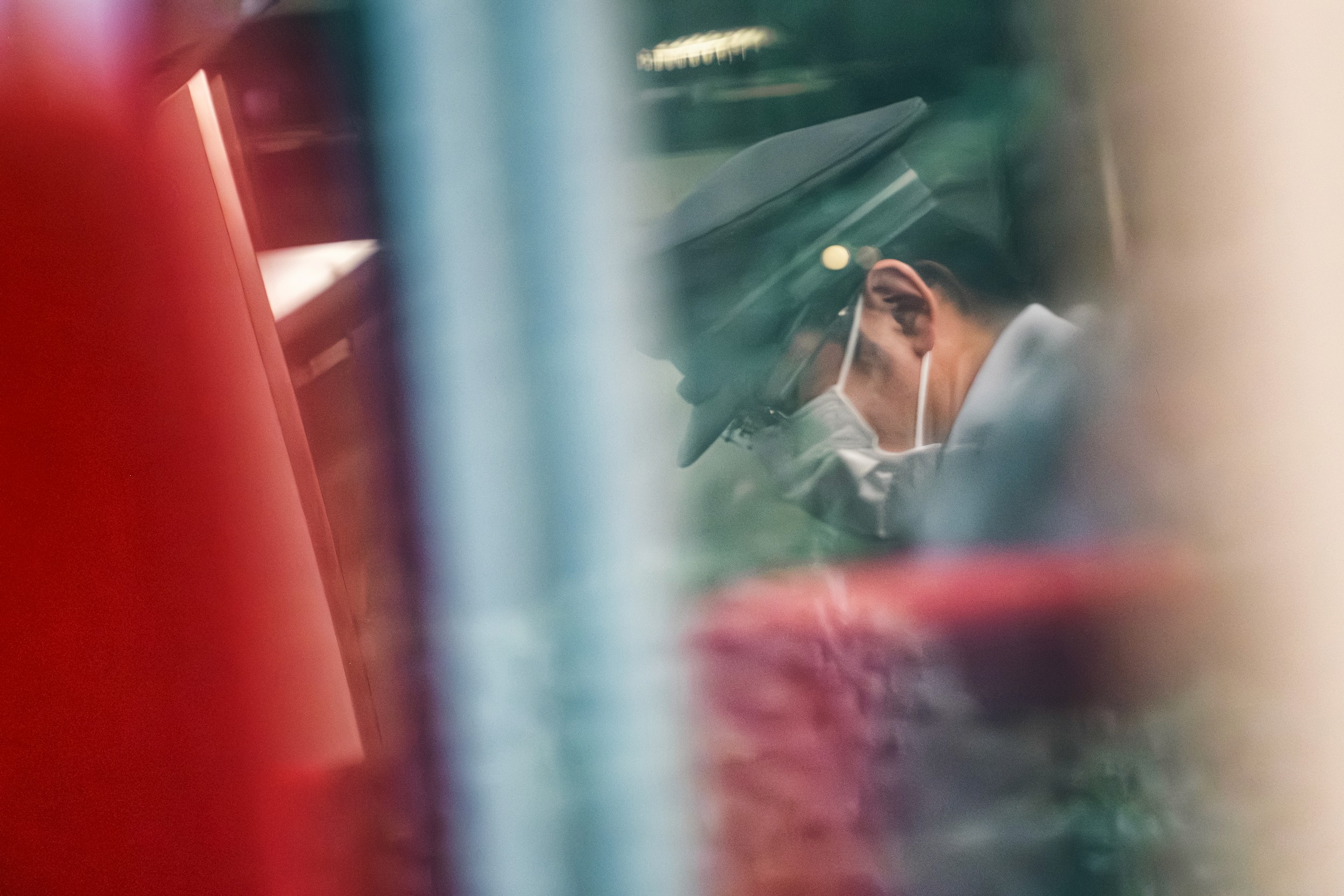 A person is seen talking on a phone, partially obscured by reflections and blurred elements in a vibrant setting.