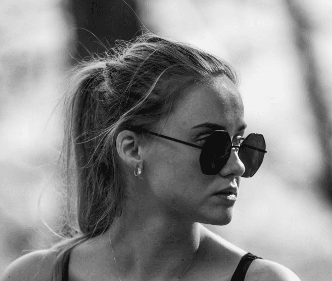 a young man wearing glasses standing in front of a mountain