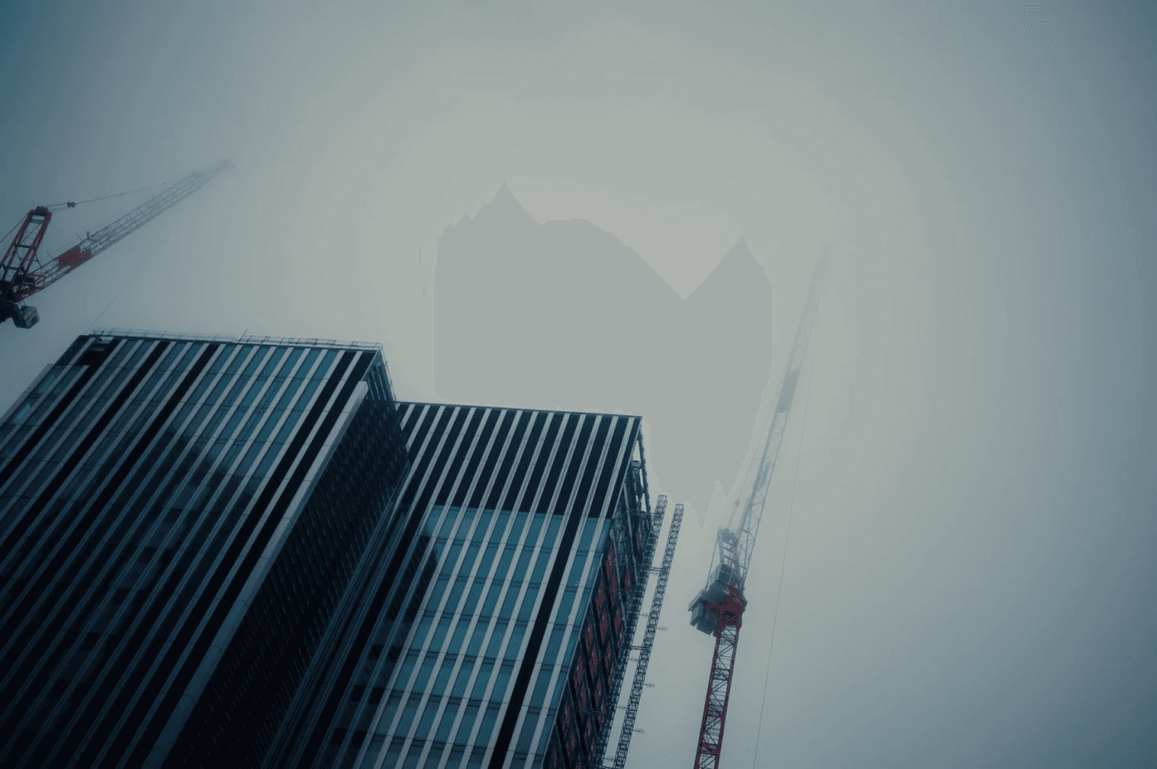 A smiling man and woman in black shirts sitting together outdoors, engaged in conversation, with a white building in the background.