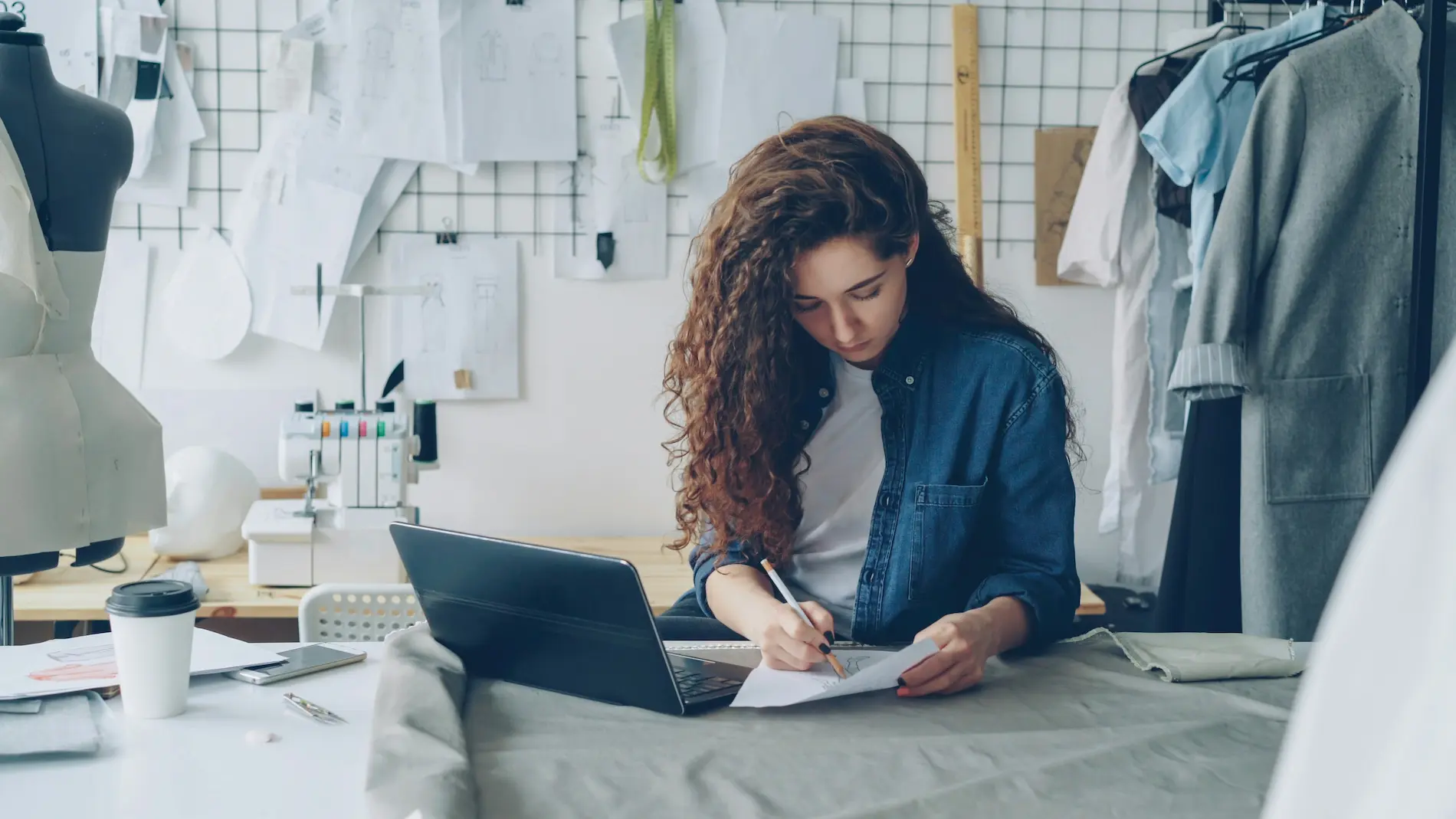 person holding pencil near laptop computer