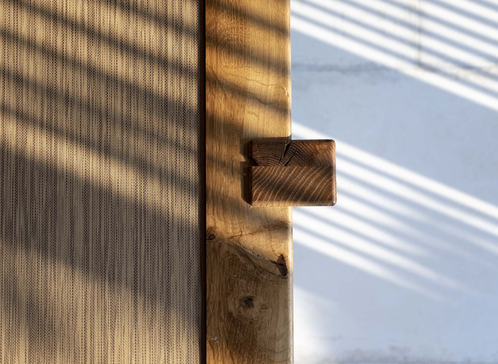 光影灑落於以木榫技法製作的門把細節與編織材質門板，展現日式細木工工藝