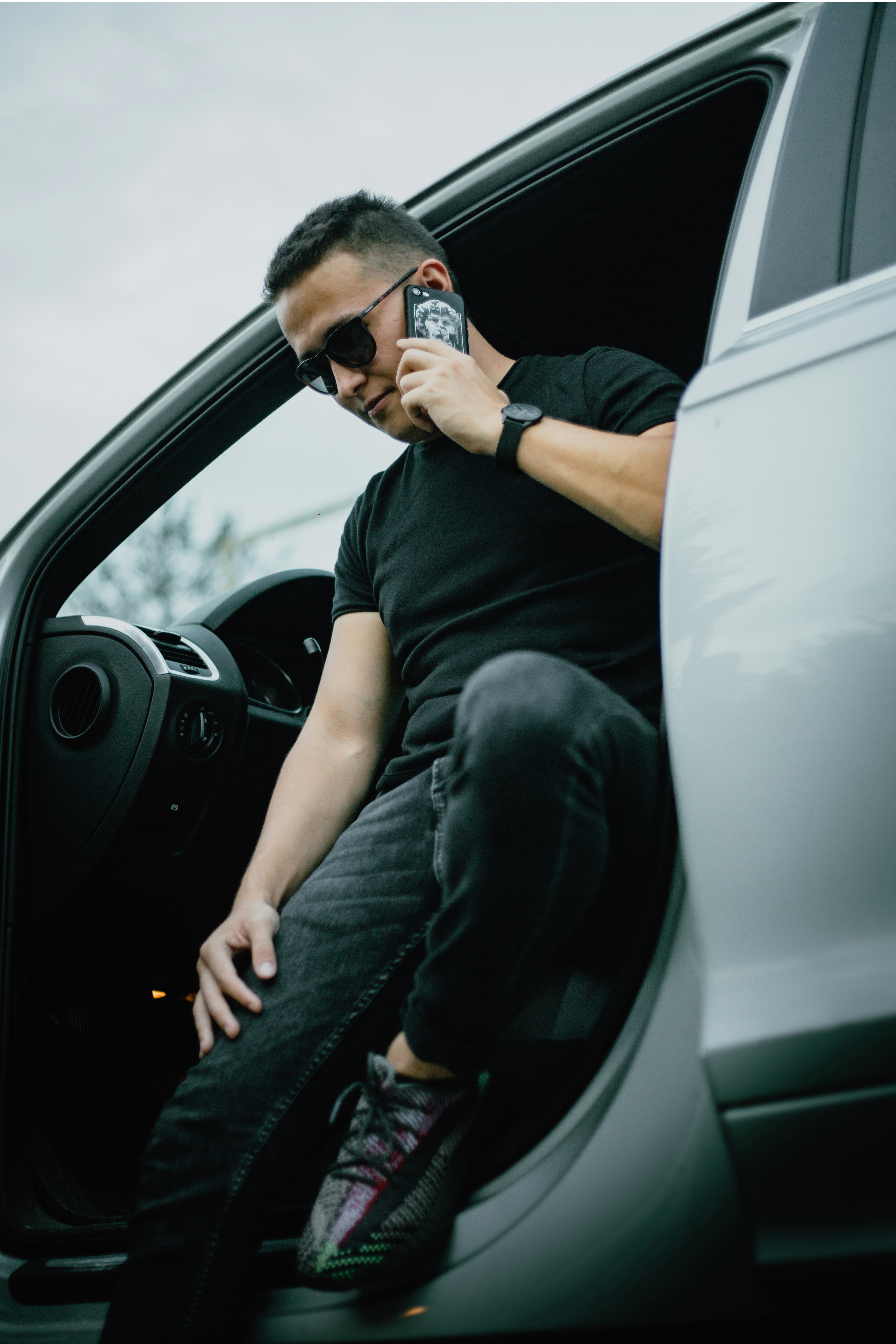 man in black t-shirt and blue denim jeans sitting on drivers seat