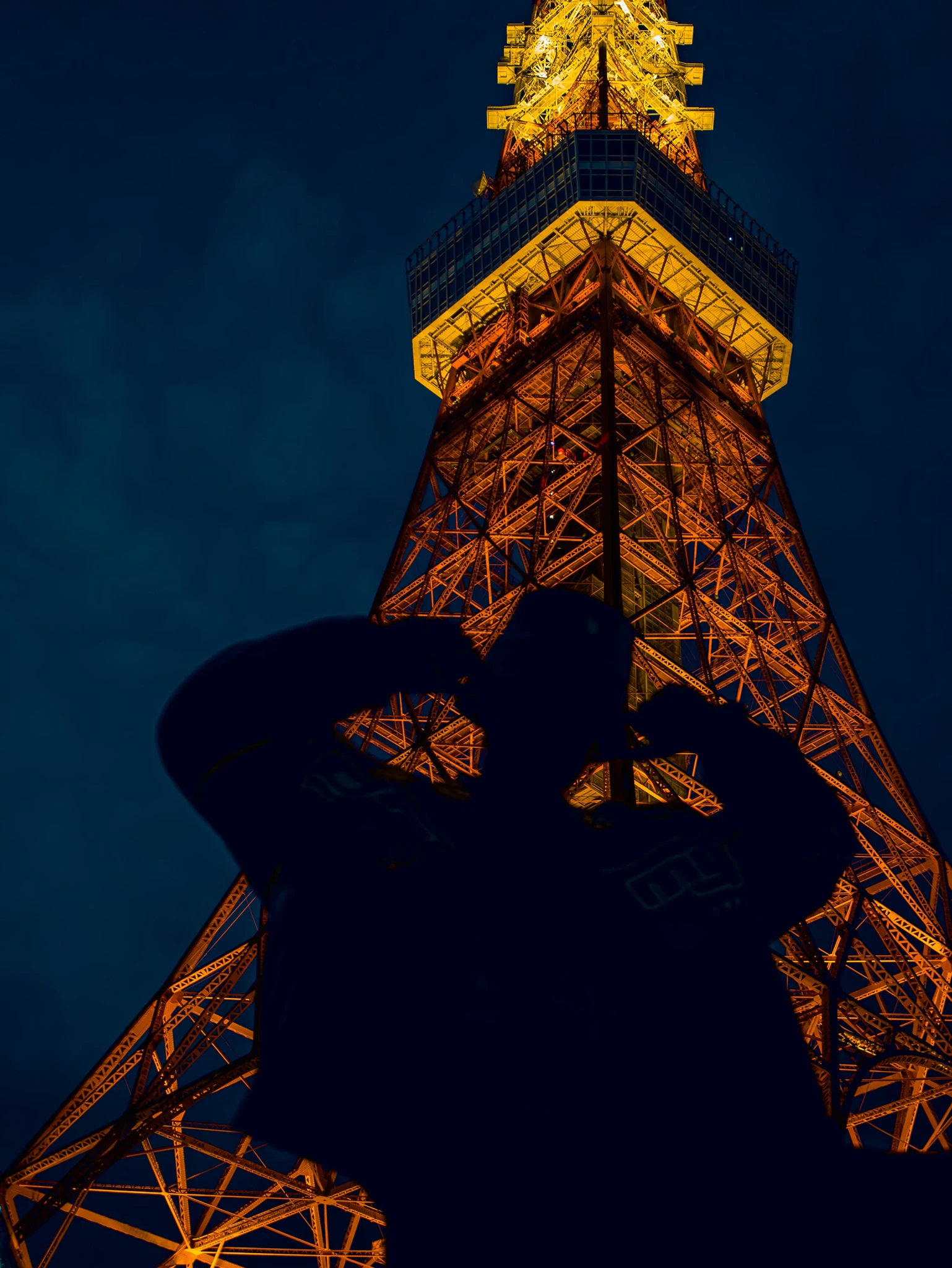 A shadow in front of a picture of a night iluminated Tokyo Tower