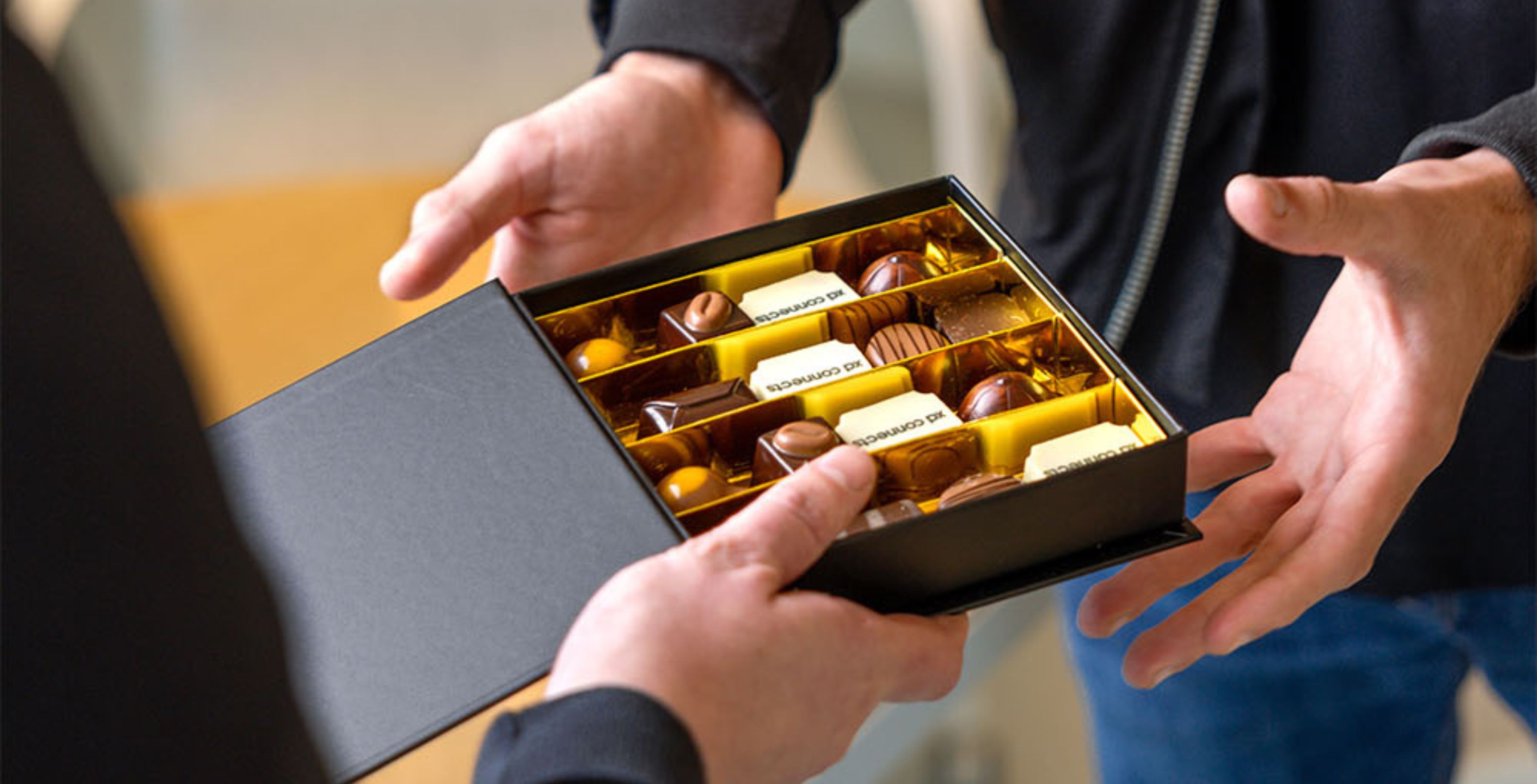 Een zwarte doos met verschillende soorten chocolade die wordt uitgewisseld tussen twee mensen