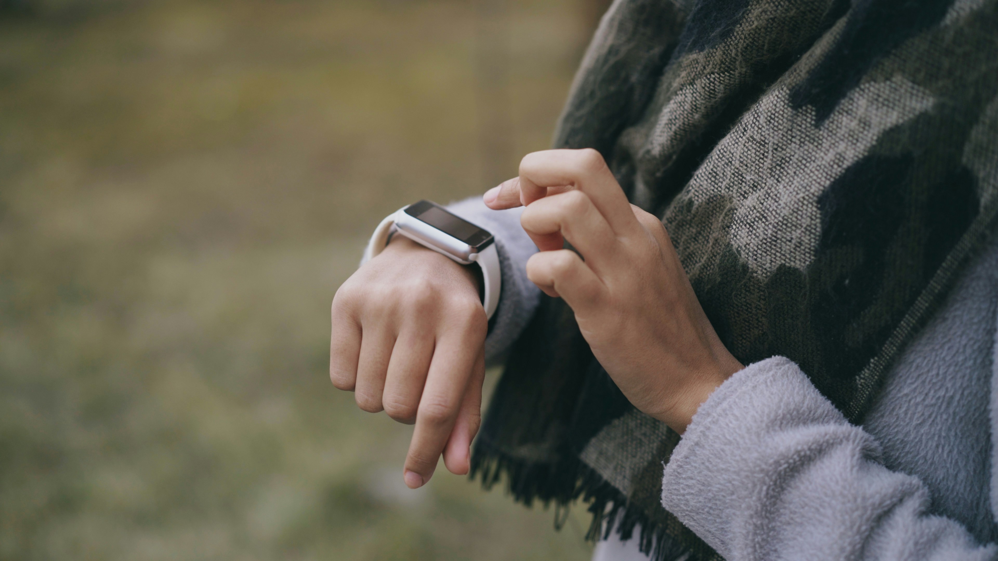 Person checking a smartwatch outdoors with a scarf