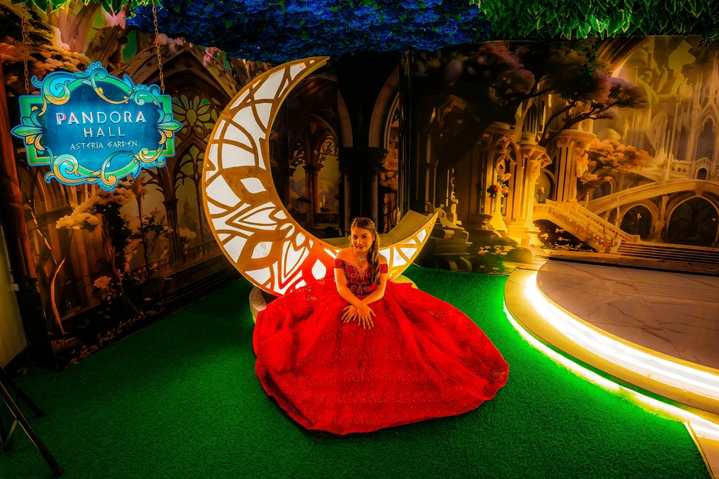 Debutante in a red gown seated on the golden crescent moon at Pandora Hall, Stalla Suites QC