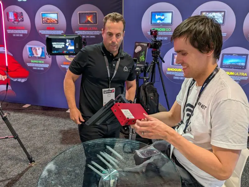 Real photo from a trade show with Anton Shmakov holding MR·NET cellular bonding gateway with one of MR·NET clients nearby