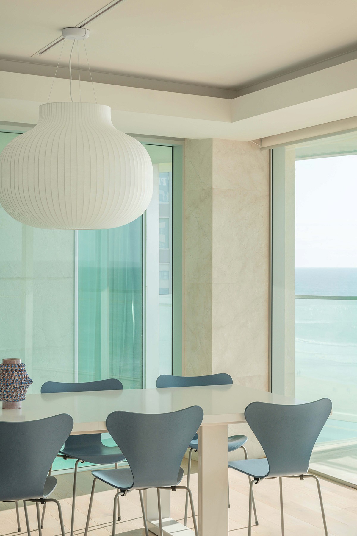 High Tide apartment dining area with sculptural pendant light, coastal seating, and floor-to-ceiling glazing overlooking Surfers Paradise ocean views.