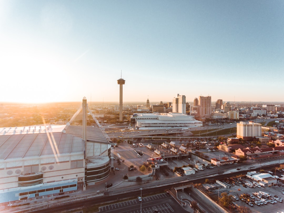Aerial view at sunrise showing a domed arena, a tall observation tower, and a compact downtown skyline beyond.
