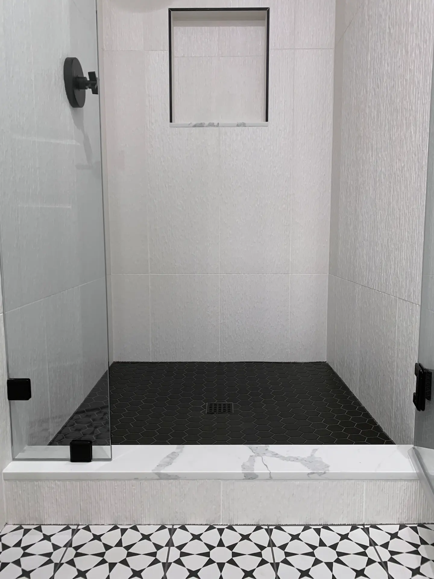 Closeup of the guest bath shower enclosure, highlighting the contemporary black fixtures and sleek tile work. Photo by Todd Huge.
