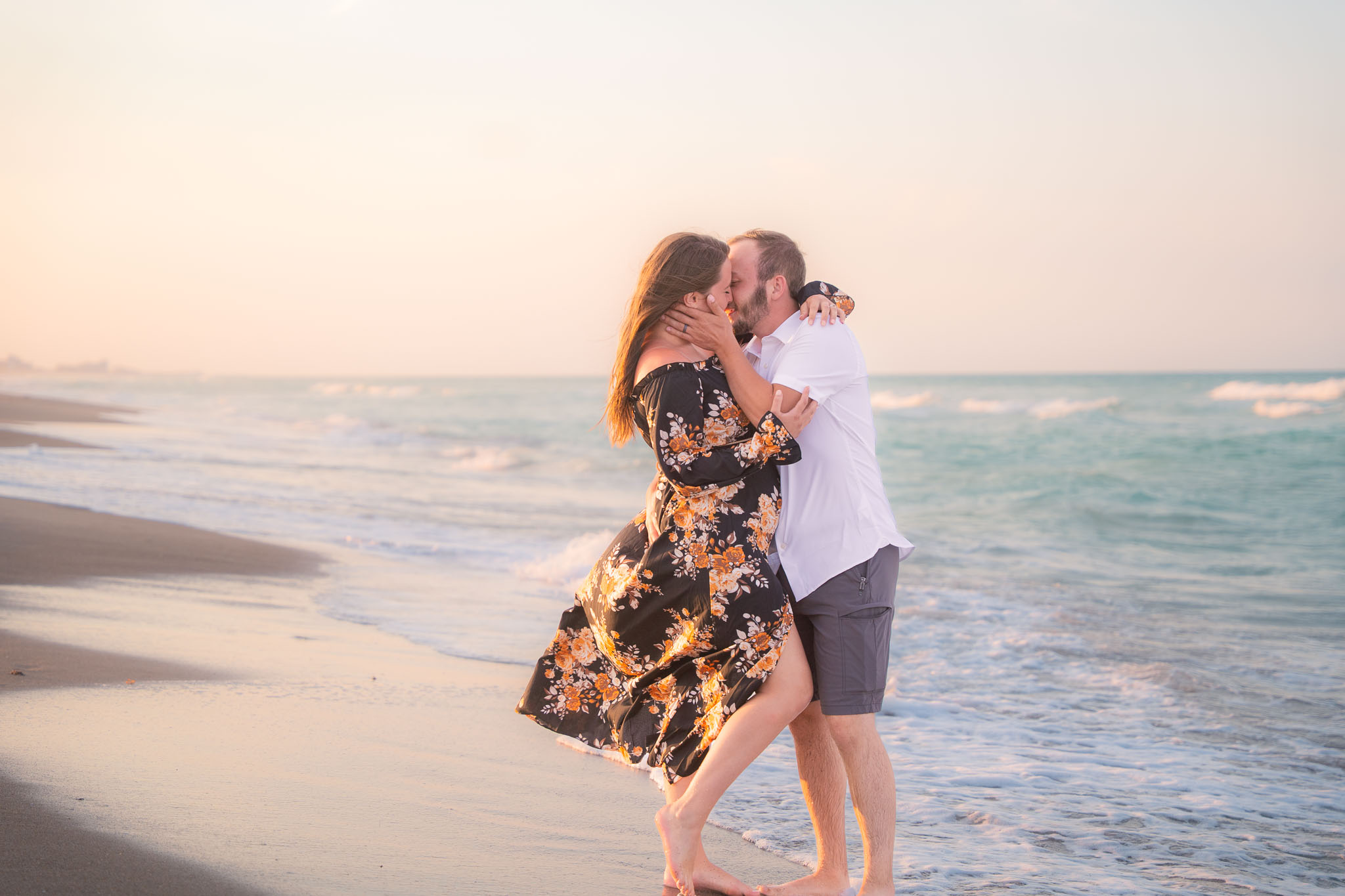 A couple in a gentle embrace, standing on the beach in front of the ocean
