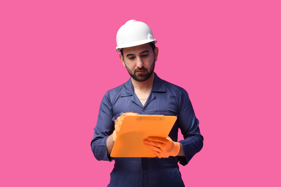 close-up of a worker in high-visibility clothing looking at a digital map on a mobile device, industrial containers and a shipping crane in the background