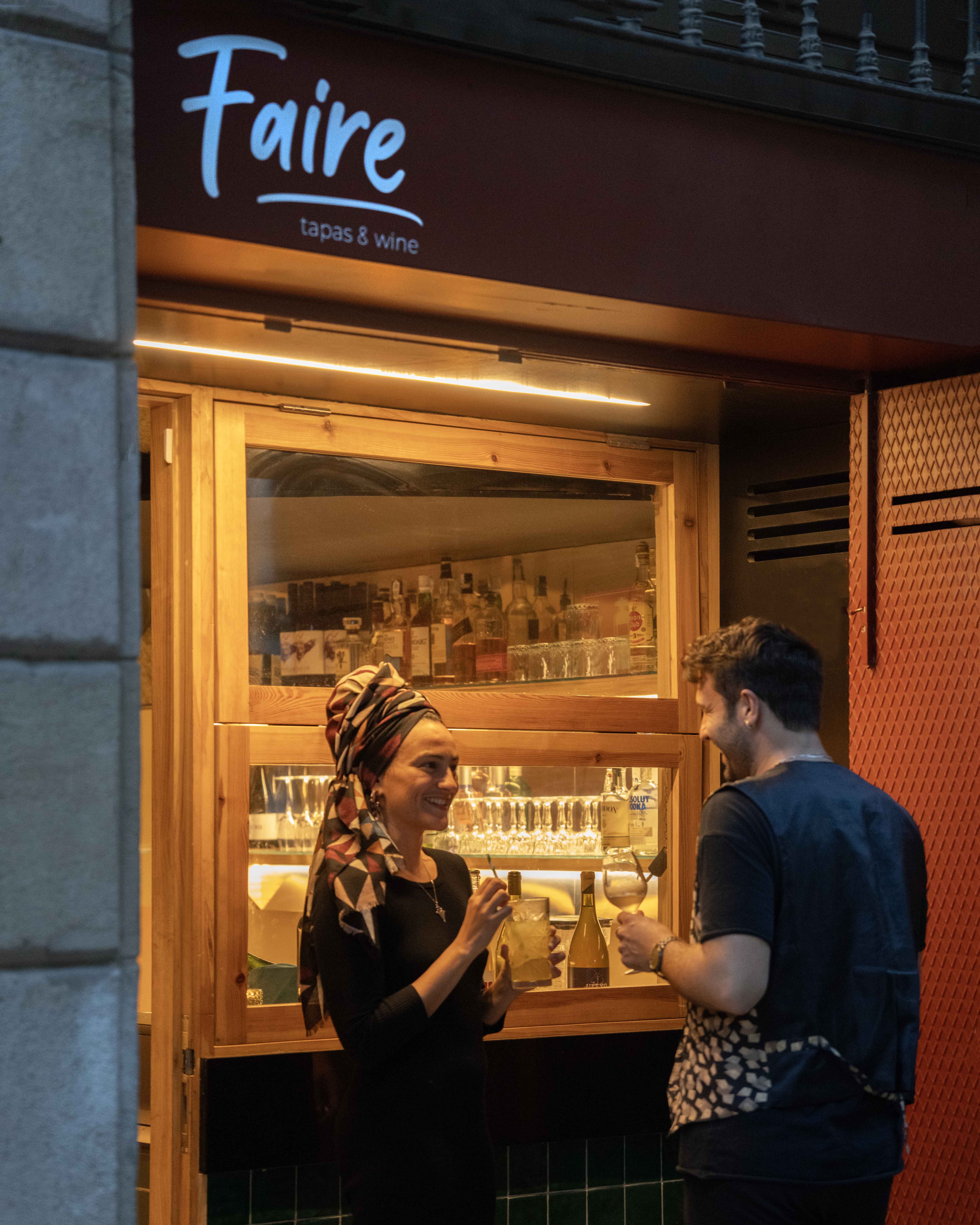 Invitados disfrutando de bebidas frente a Faire. Tapas & Wine, Carrer de Girona