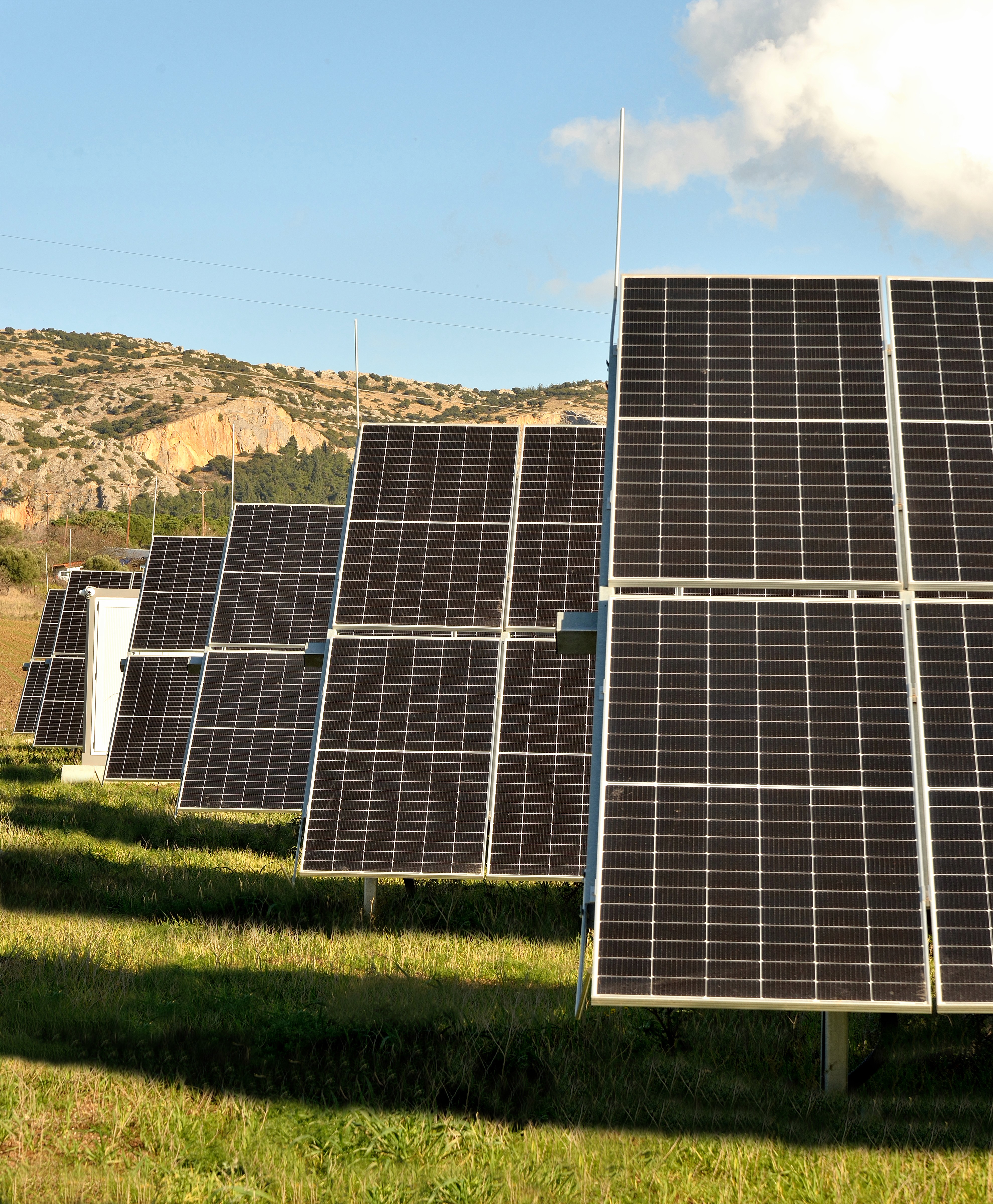 Angled ground-mounted photovoltaic panel rows optimized for solar exposure in utility-scale installation