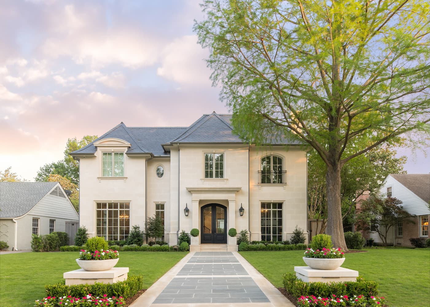 Symmetrical front yard landscape design with geometric walkway and matching planters at French country home in Park Cities Dallas