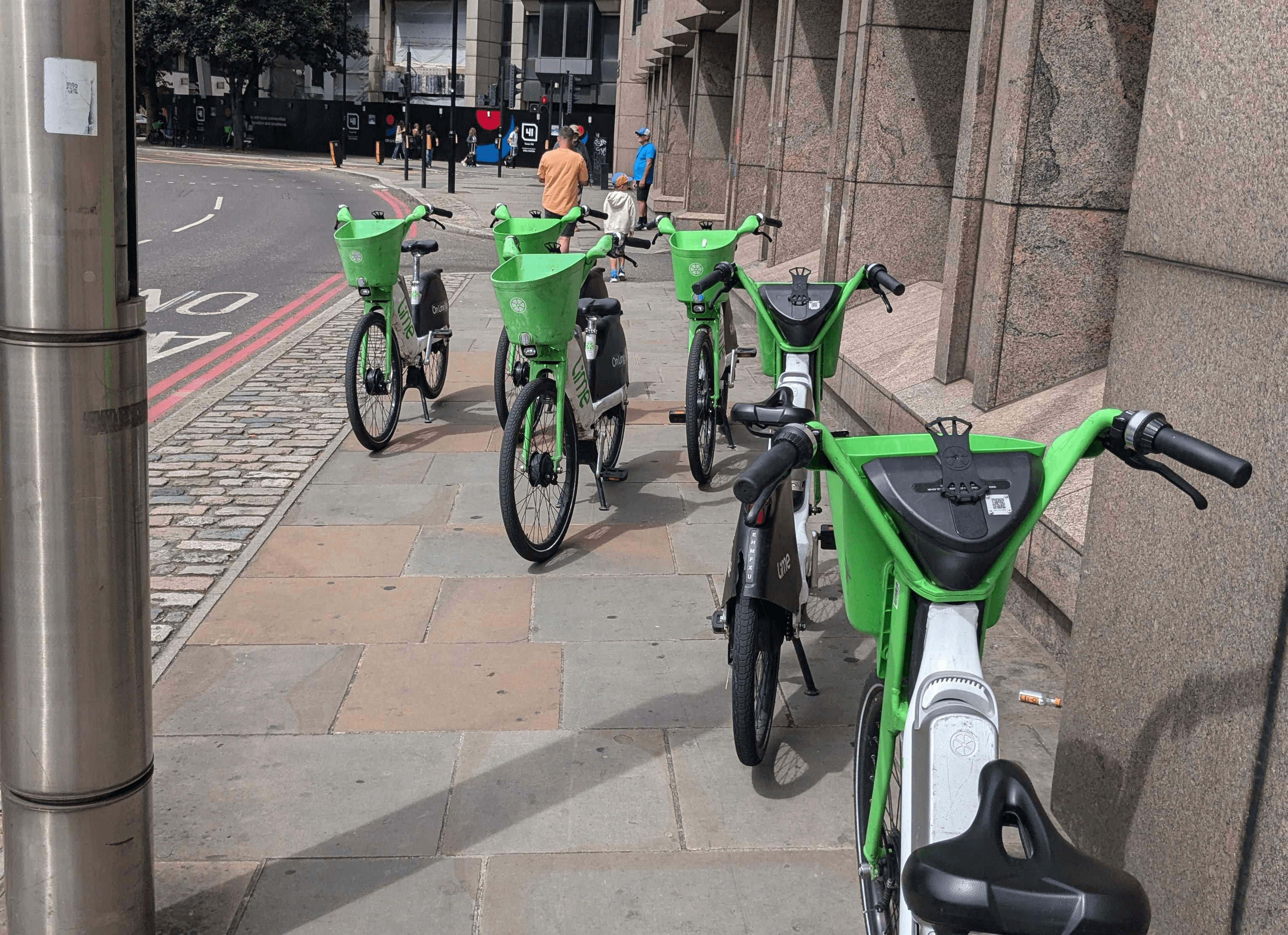Five e-bikes on a pavement obstructing the path through.