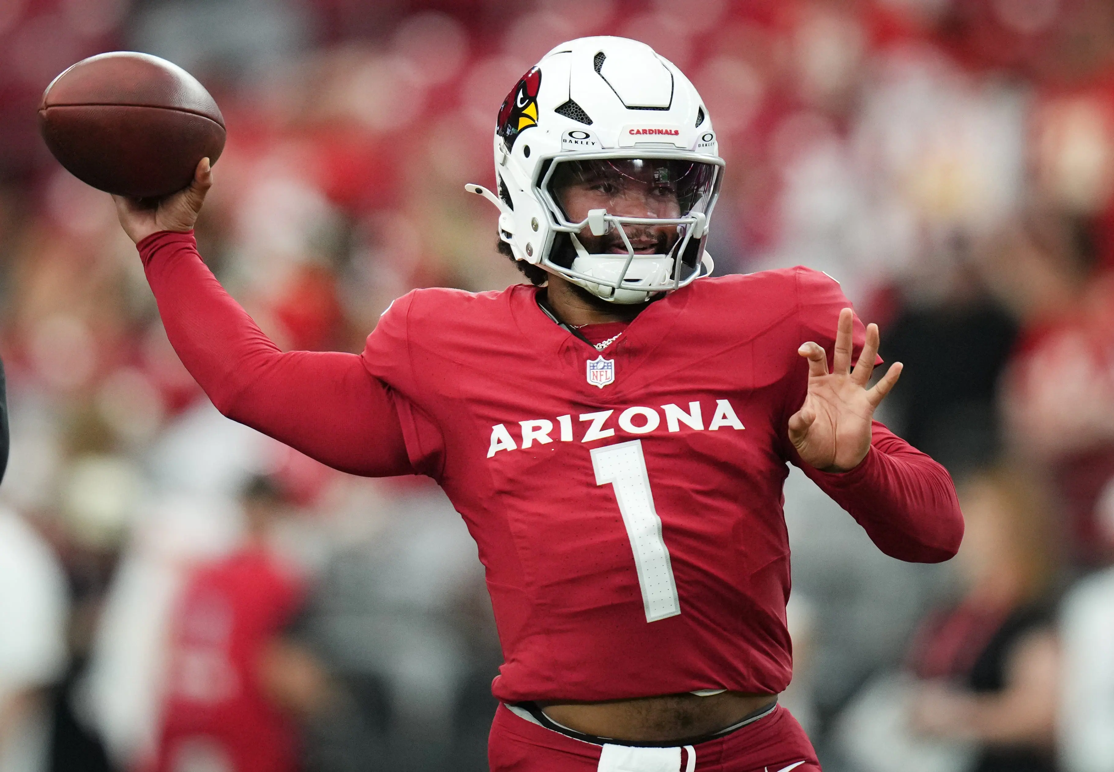 Arizona Cardinals quarterback wearing a red jersey with number 1 preparing to throw a football during a live NFL game.