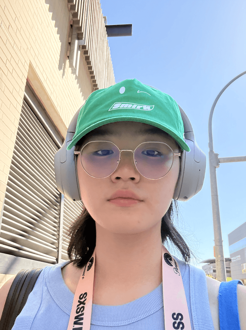 A selfie of Natasha wearing a green hat and a SXSW lanyard