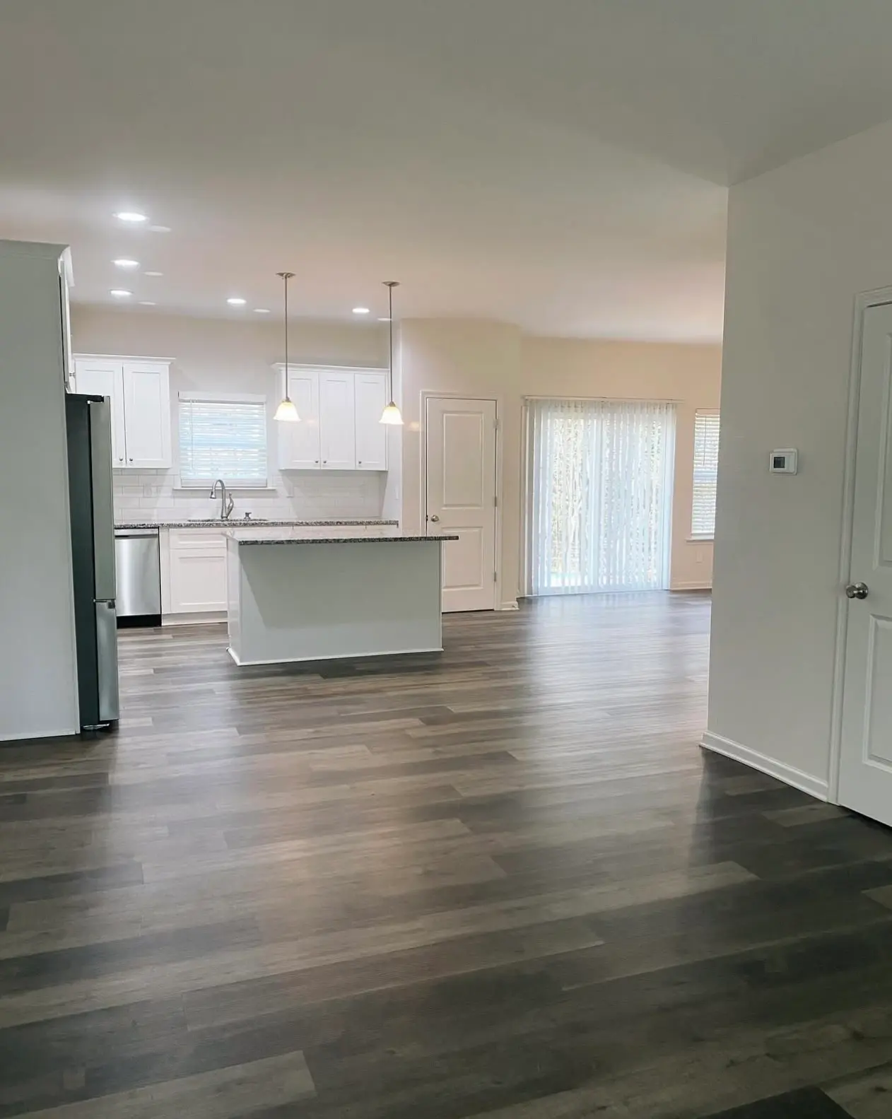 "Move-in ready open-concept kitchen and living area with sanitized white cabinetry, polished countertops, and spotless grey wood-plank flooring.