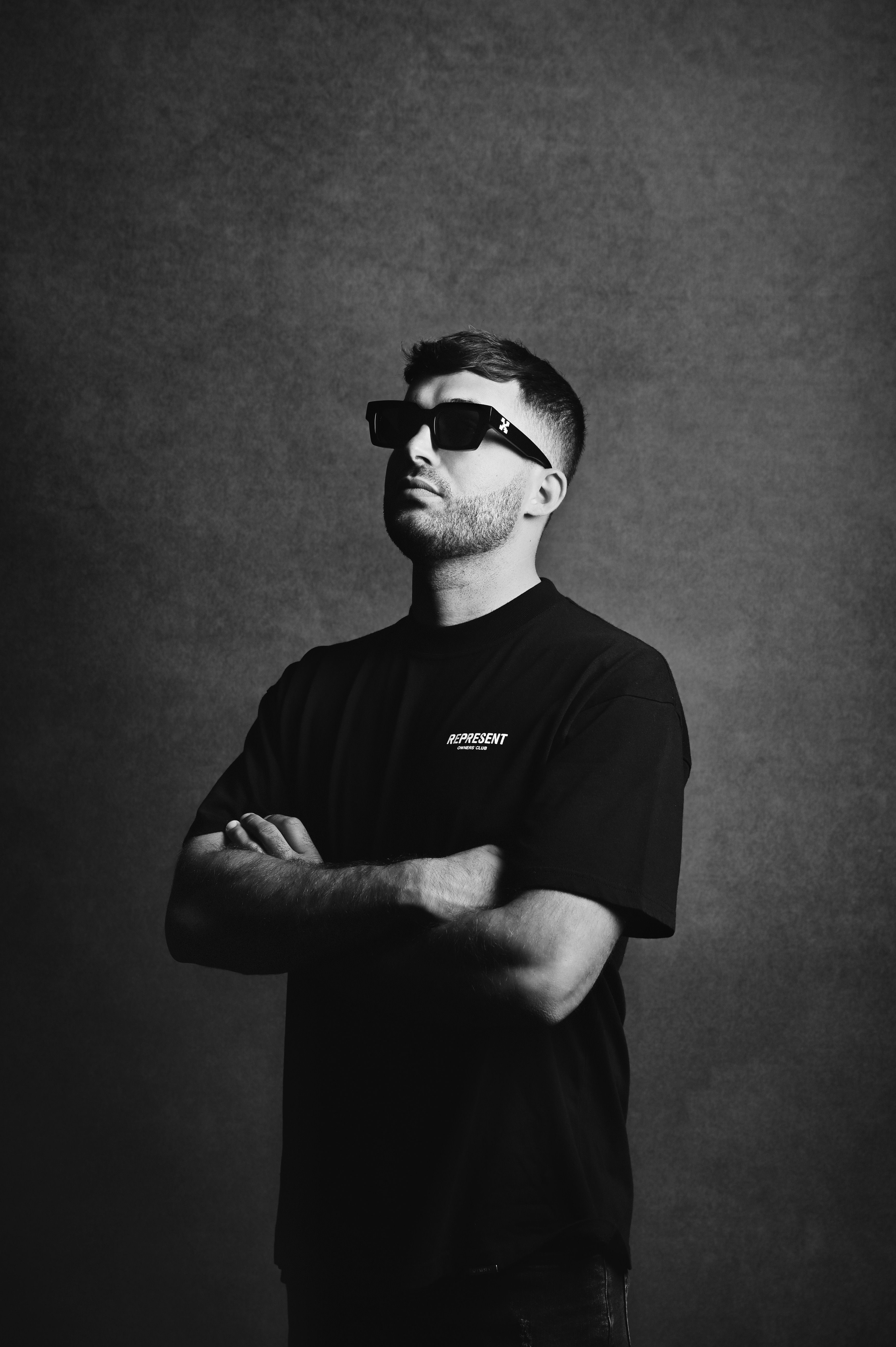 Portrait of a man in sunglasses with arms crossed, black and white