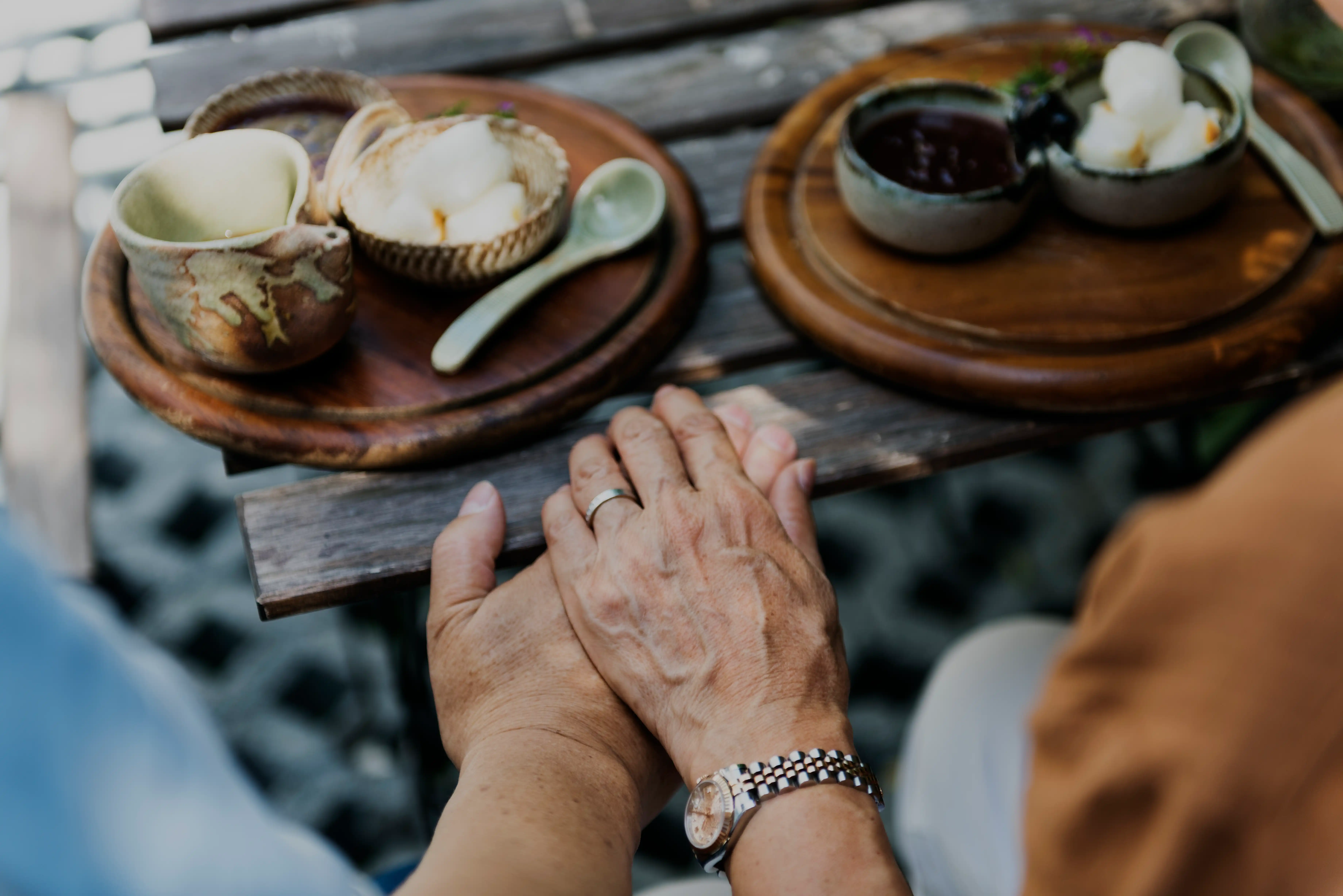 Senior guests holding hands while enjoying Ayurvedic snacks and herbal refreshments at Au Revoir Wellness Resort, Kerala.