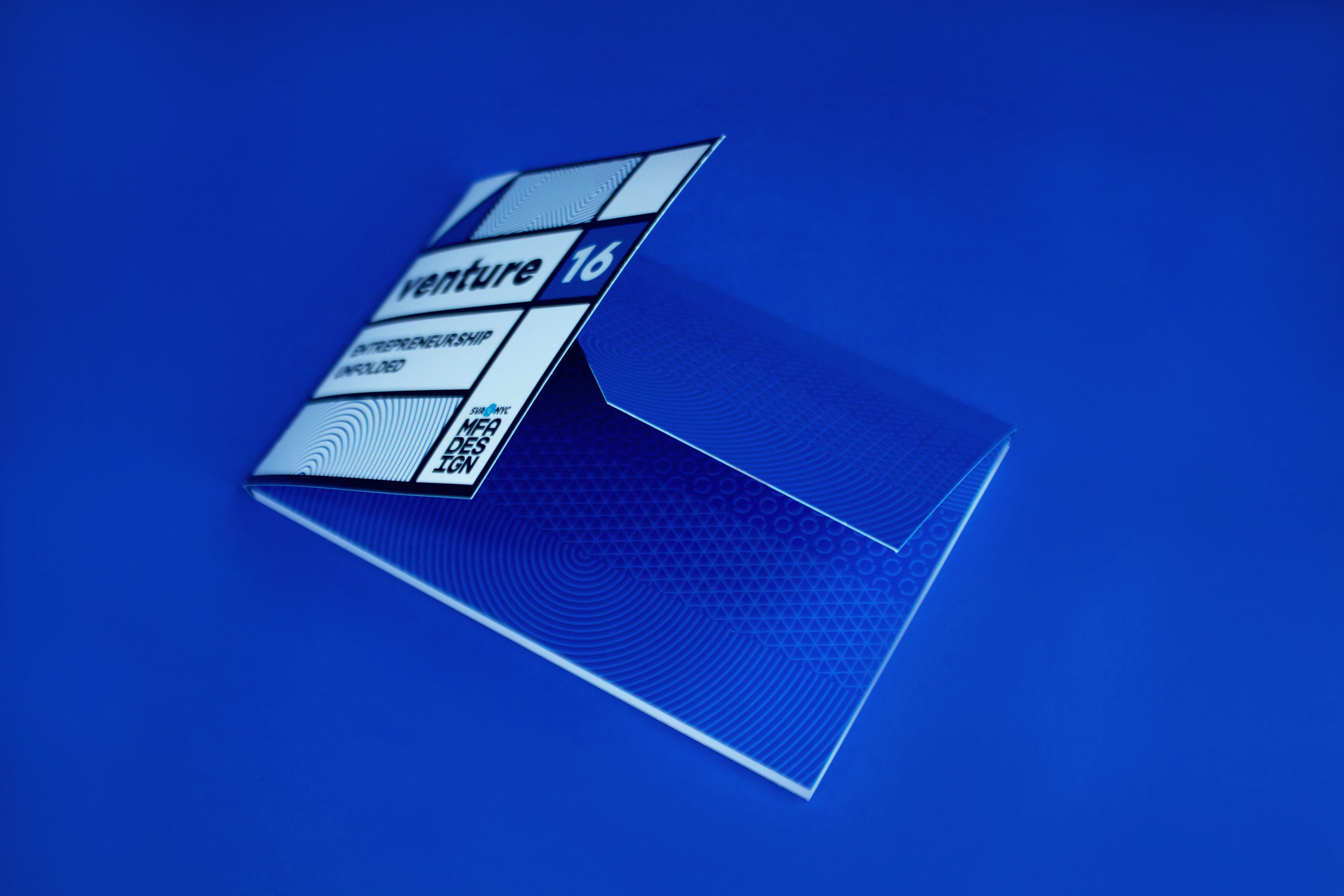 A blue envelope with some white rectangles on which there is the text: venture 16 Entrepreneurship Unfolded MFA Design SVA NYC logo.