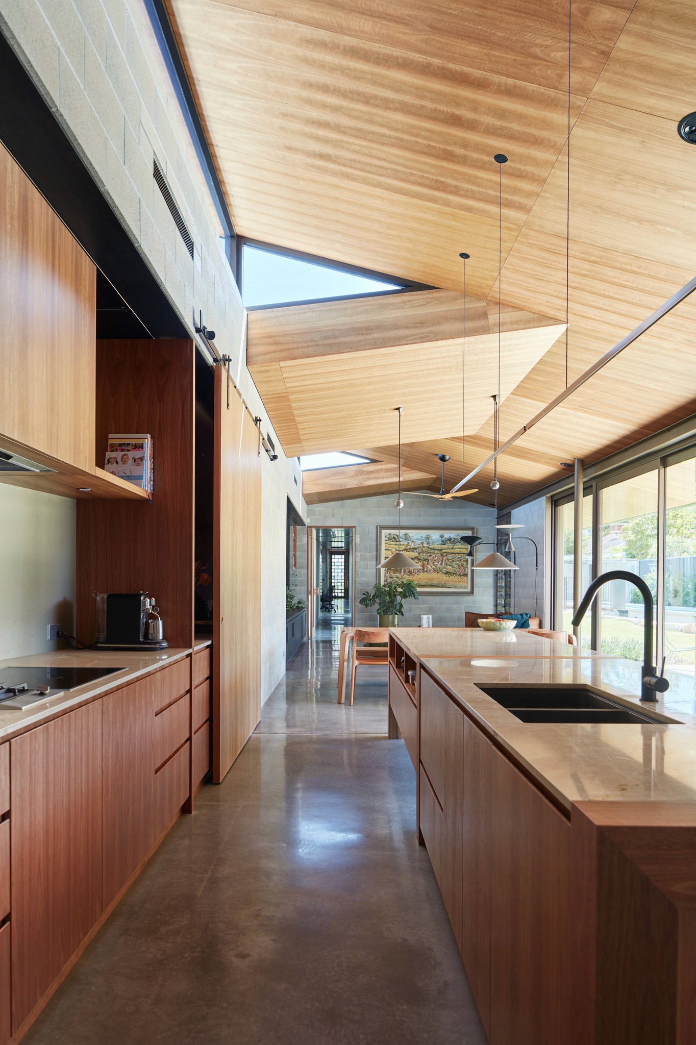 Modern kitchen with a wooden dining table, white chairs, and a hanging light fixture above.