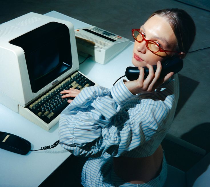 Person on a landline phone next to a vintage computer terminal, representing calling for help after a BitLocker lockout