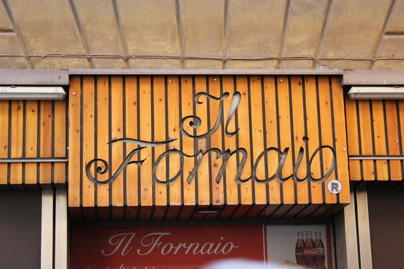 il fornaio shop name is engraved in pieces of wood above the entrance