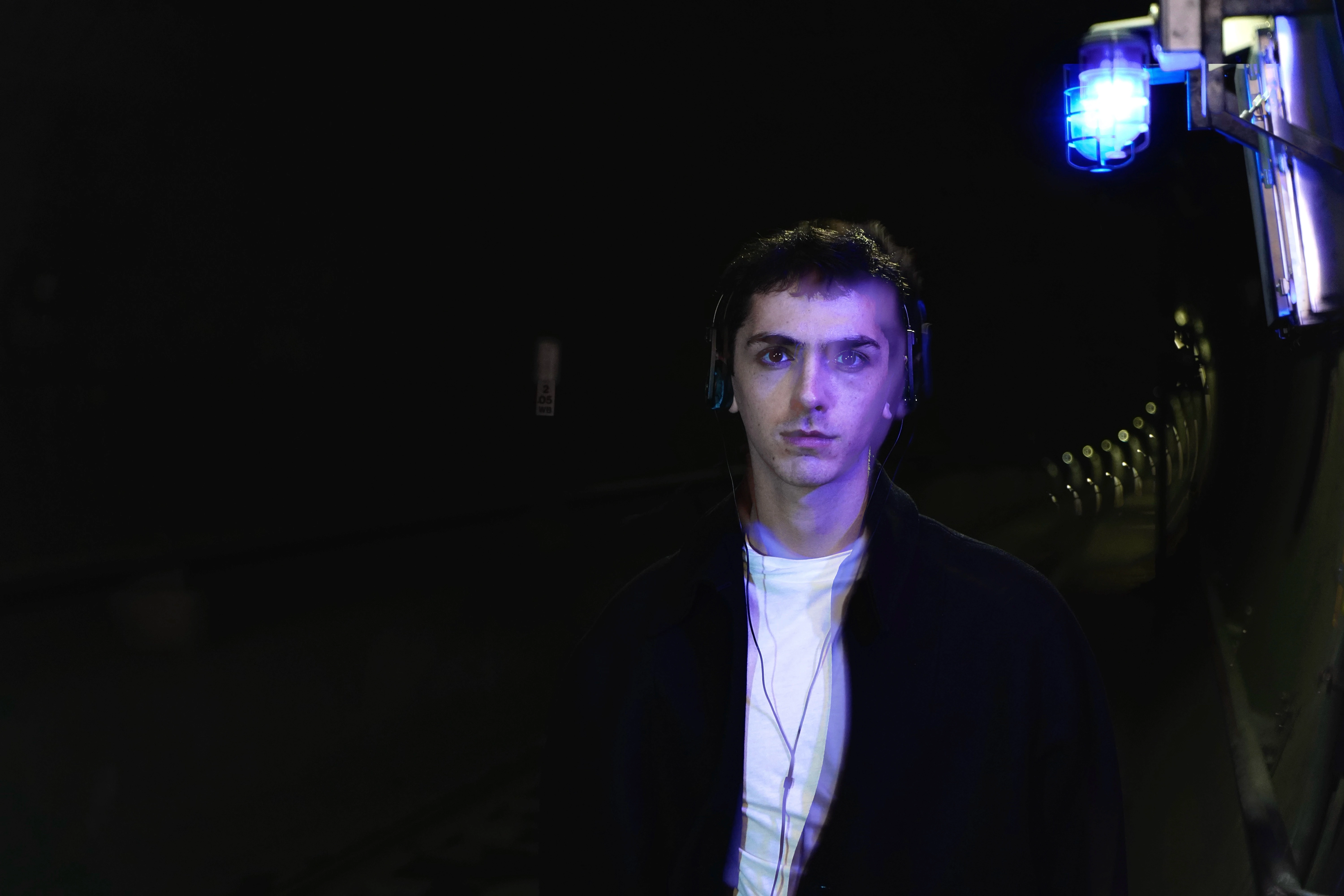 Rllyevan drenched in the blue light under a public transit tunnel