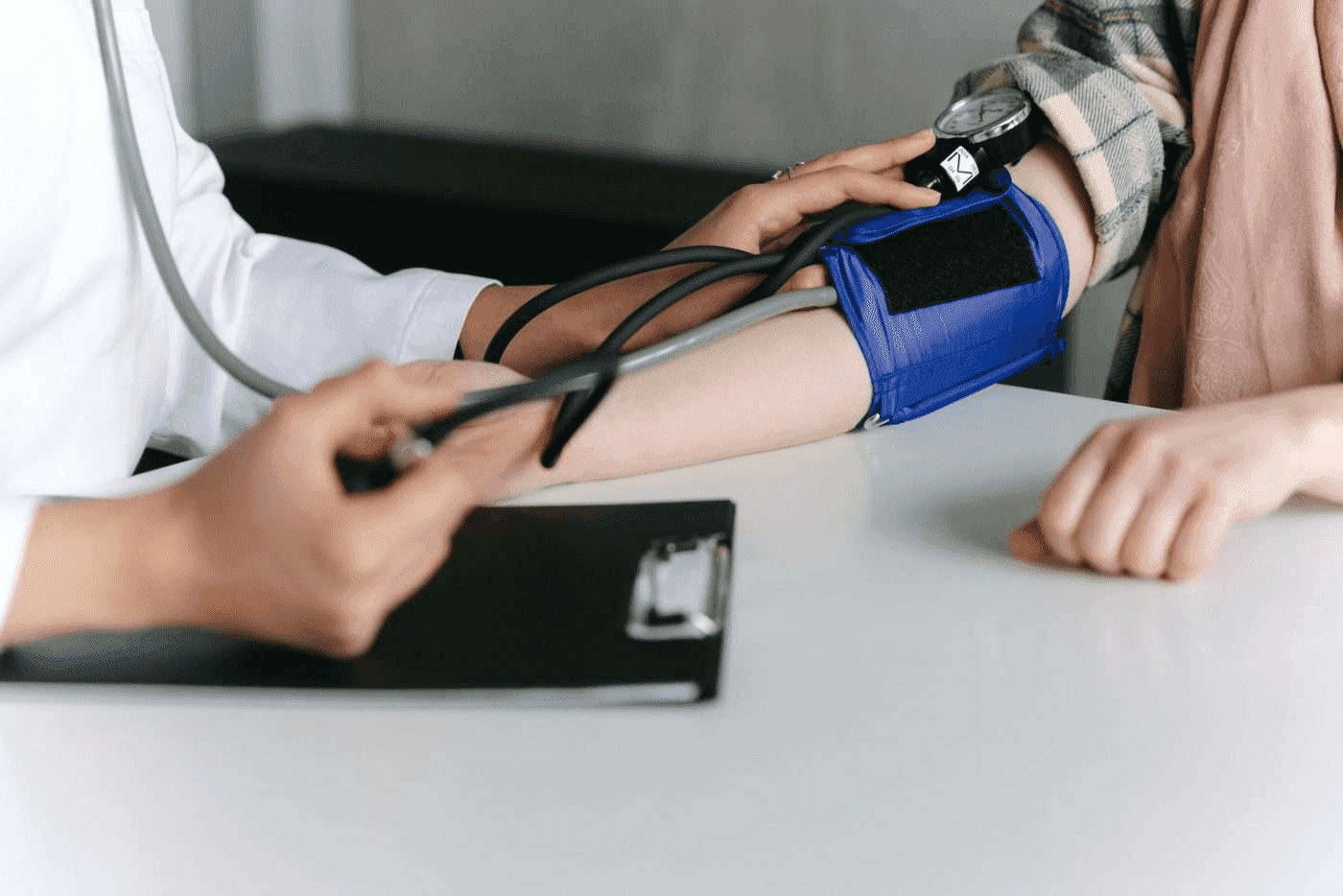 A clinician checking a patient's blood pressure using a manual cuff.