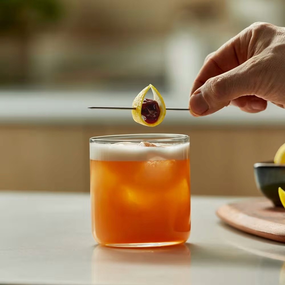 A close-up of a hand wearing multiple decorative rings against a blue background.