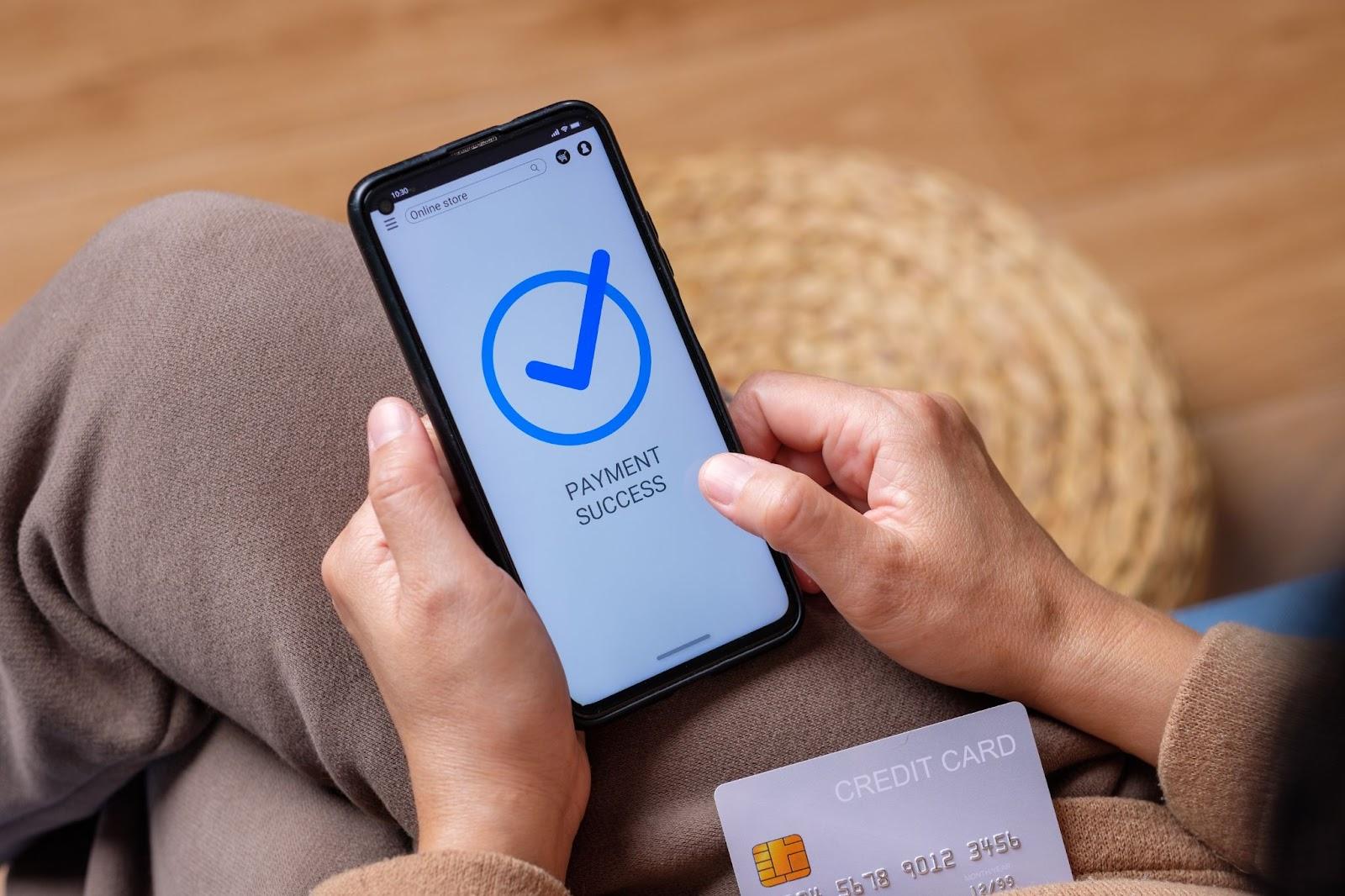 Person holding a phone that reads “payment success” with a check mark. 