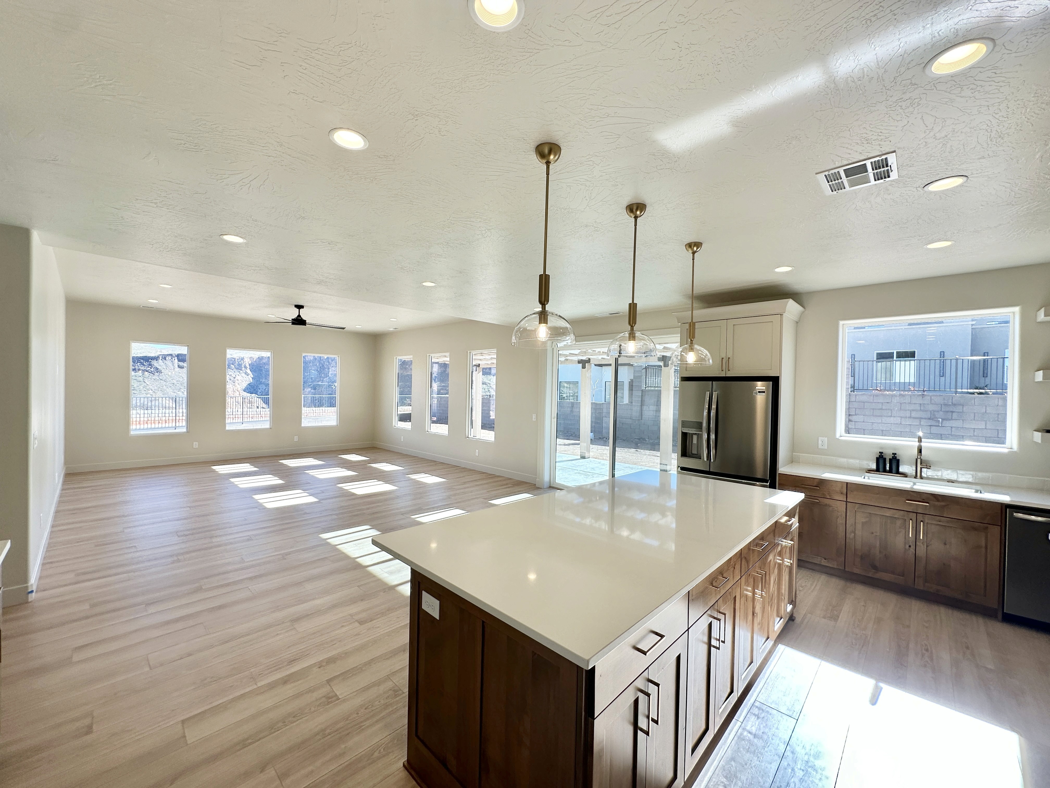 Kitchen at The View at Falcon Ridge in Hurricane, Utah, looking into the living room, featuring medium-toned wood and white cabinetry with an open, airy layout.