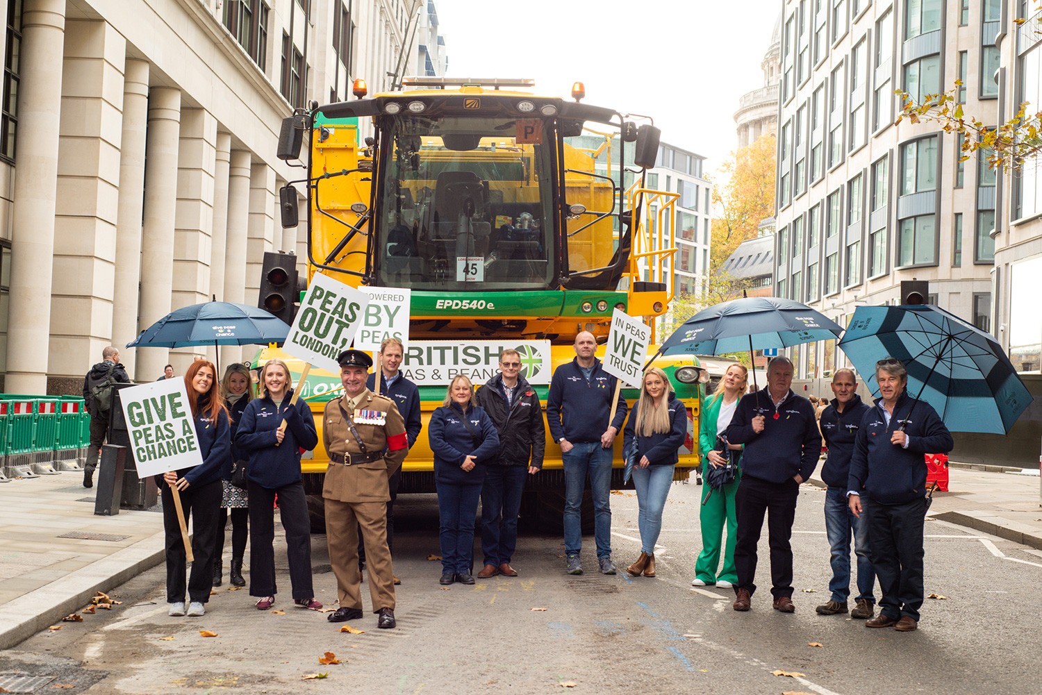 A group of people, including Fen Peas team members, standing in front of a pea viner on a London street