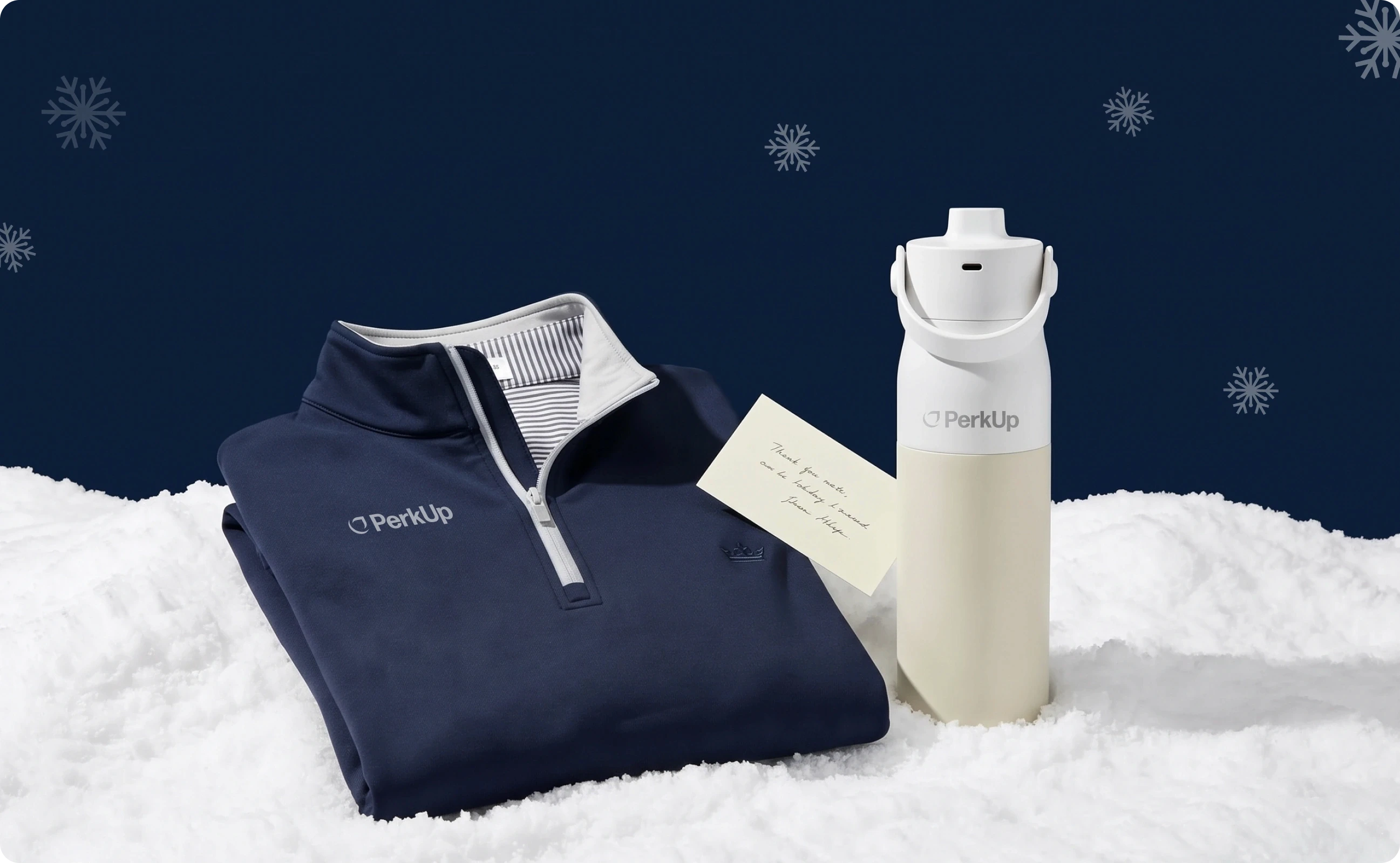A branded apparel, a note, and a drinkware on top of snow.