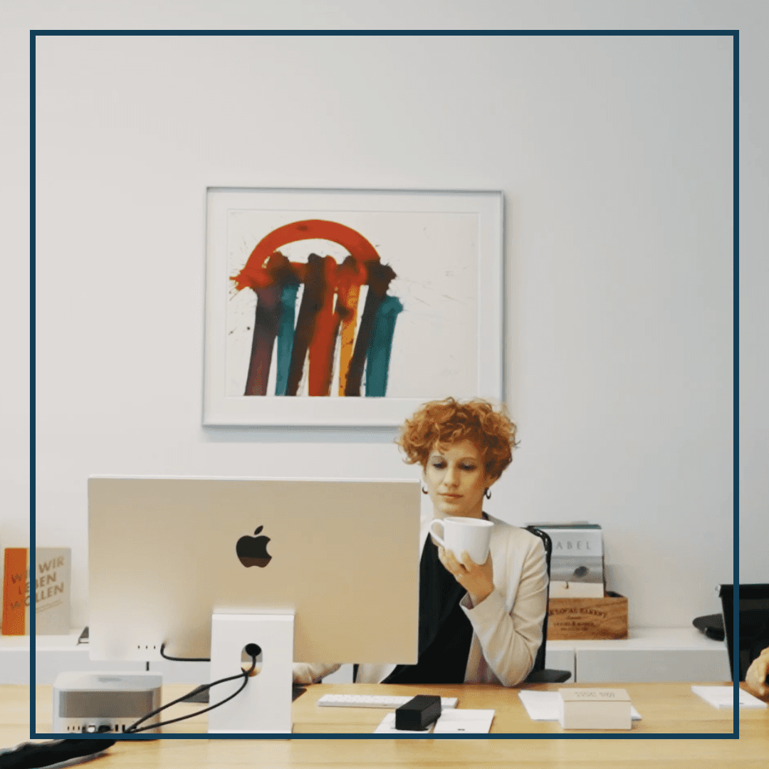 Frau an Schreibtisch mit einem abstrakten Gemälde im Hintergrund