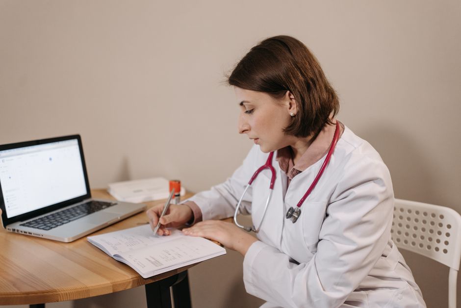 Patient discussing tracked symptoms and cycle notes with a doctor in a clinic.