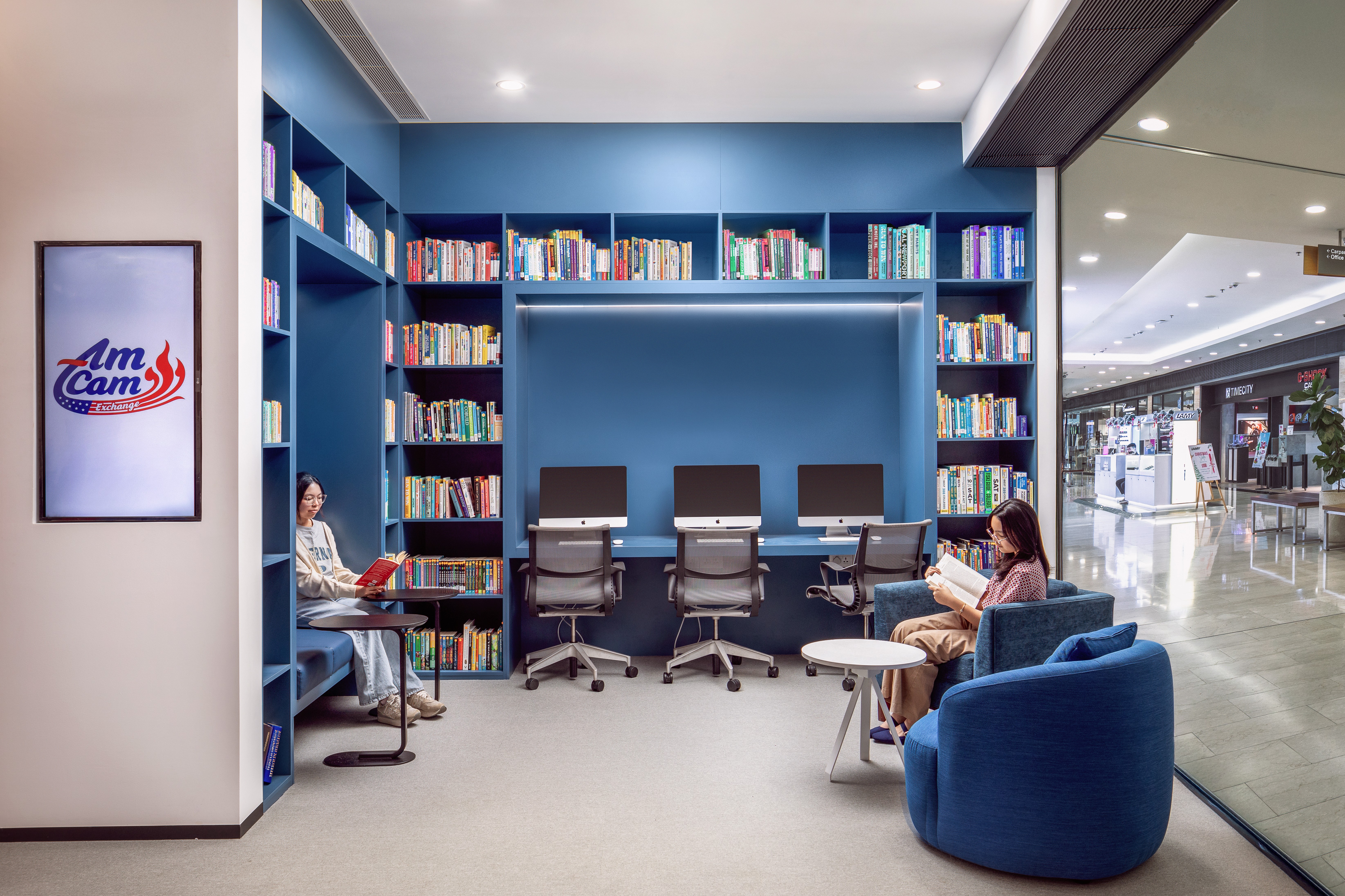 Modern library and digital learning hub featuring custom blue shelving and integrated computer stations.