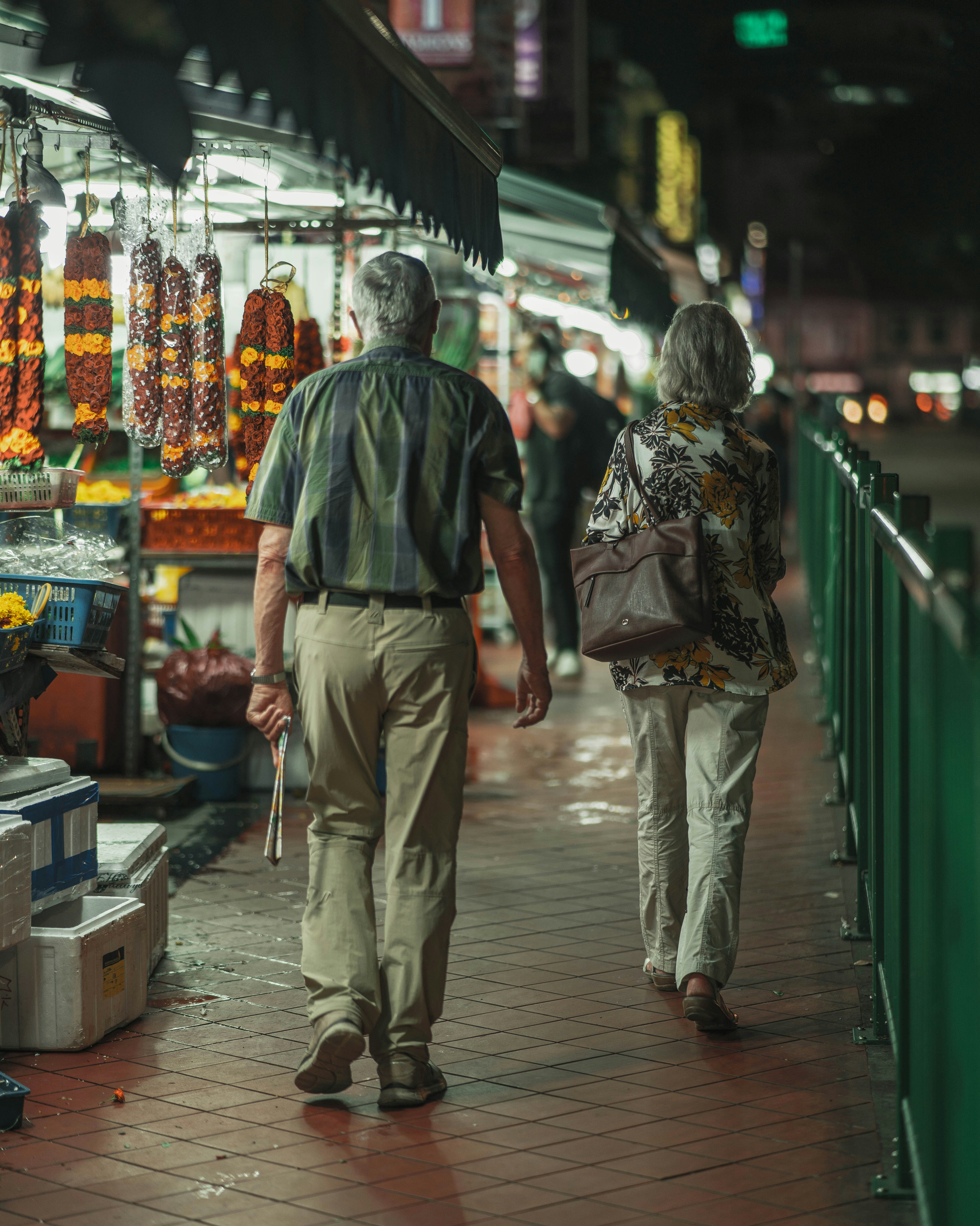 a man and woman walking down a sidewalk in a market