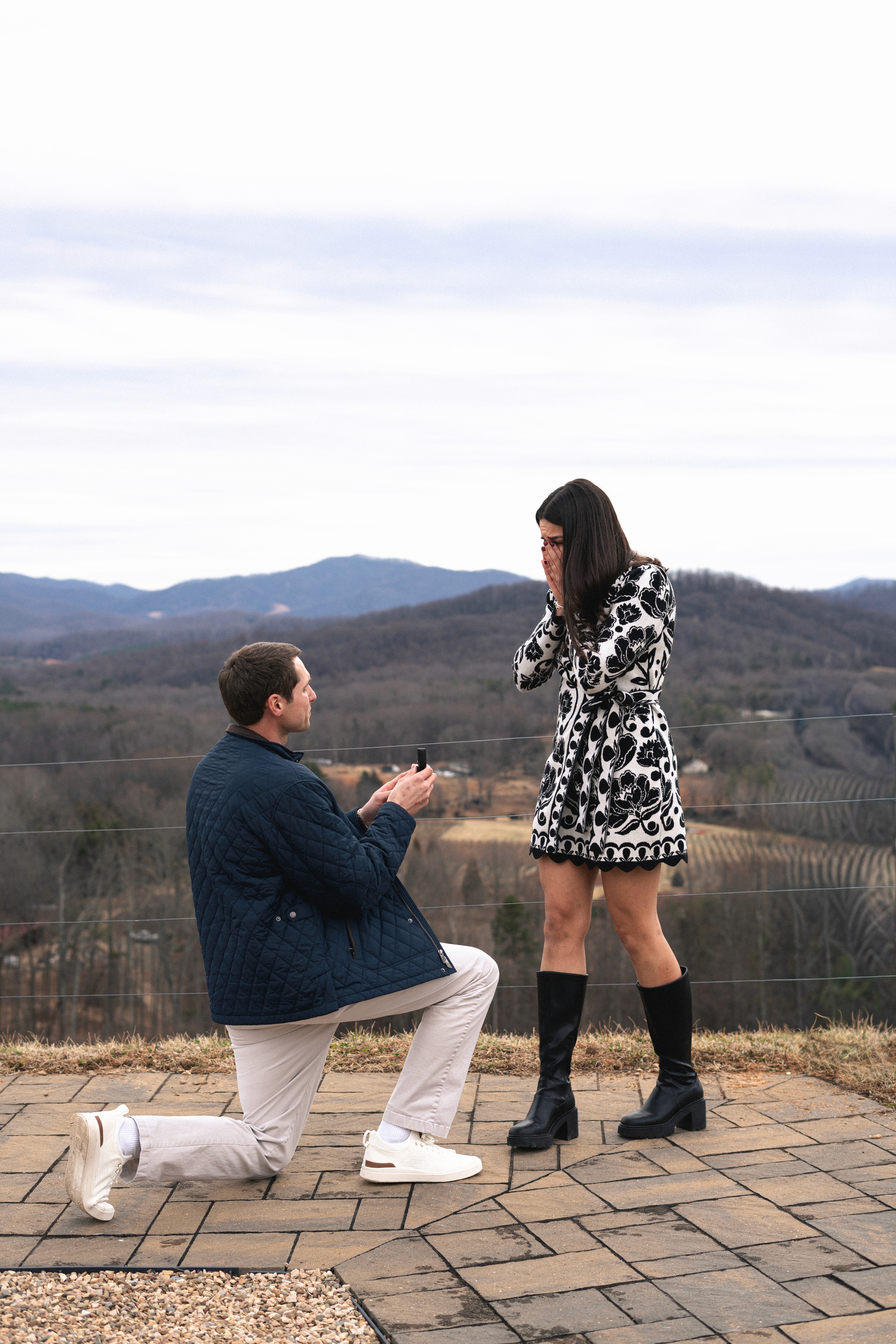 A joyful couple in formal attire stands back-to-back outdoors.