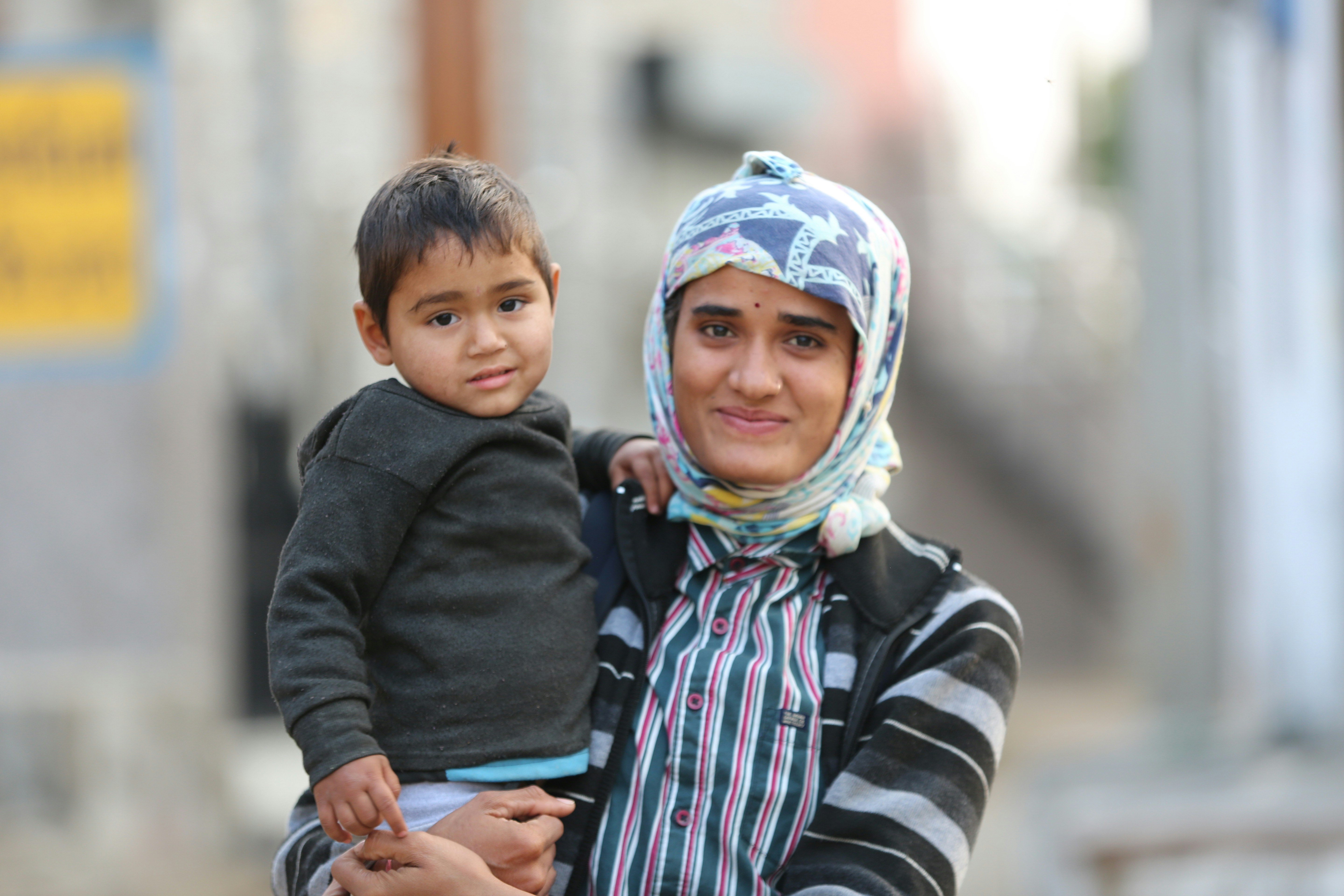 A woman holds a young child outdoors.