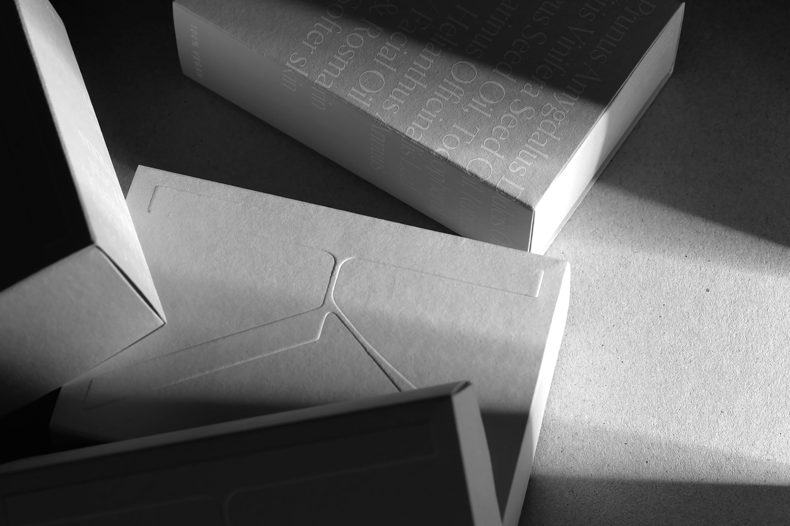 A close-up, black-and-white shot of high-quality FSC-certified paper packaging with elegant embossed typography. This detail highlights the studio's commitment to sustainable brand identity and tactile, premium print finishes for a vegan skincare line.