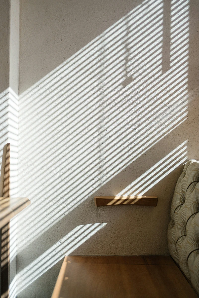 Sunlight casting window shadows across a hotel room desk.