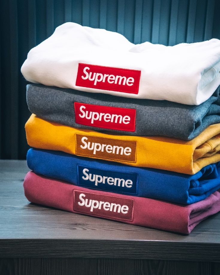 a stack of five supreme sweatshirts on a table