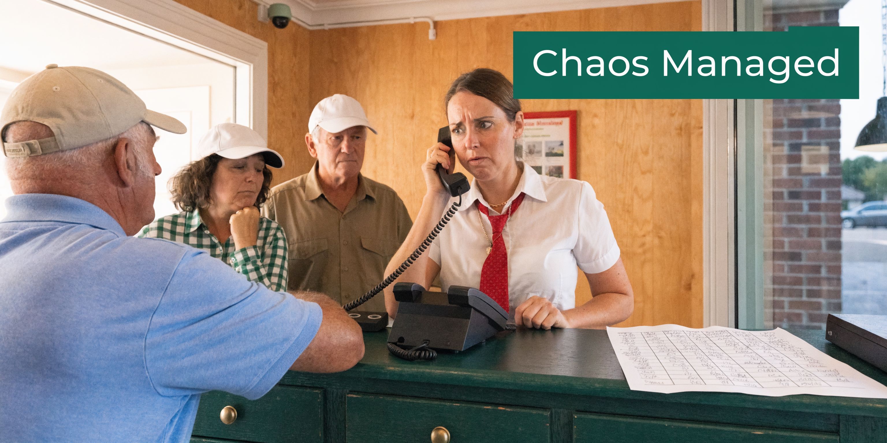 A woman at a reception desk handles a golf league check-in while talking on the telephone.