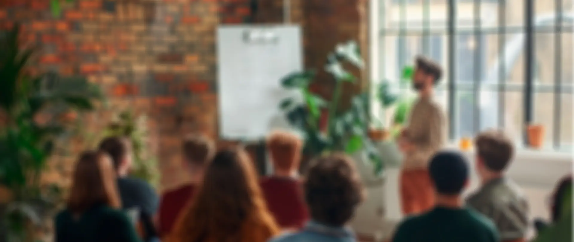 Rozostřený záběr lidí na workshopu. Ilustrace živé spolupráce a dialogu s komunitami.