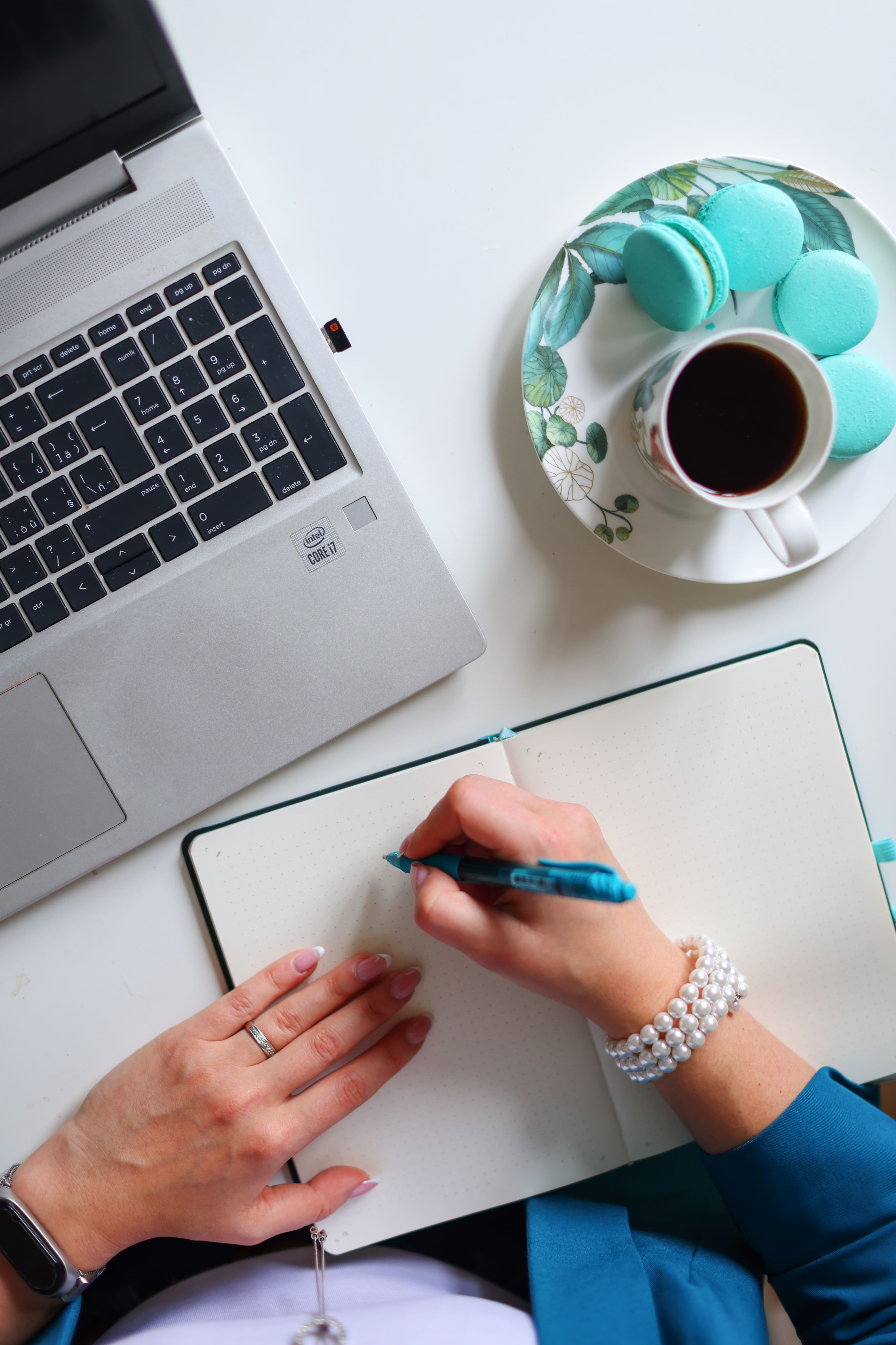 Designer writing in a notebook beside a laptop and coffee, capturing the creative planning process behind strategic website design