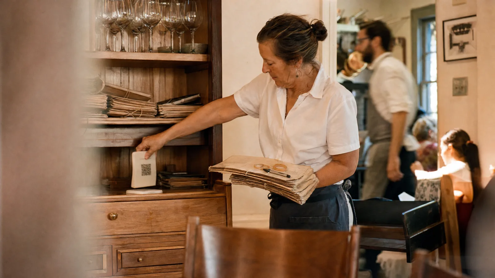 Cameriera ritira i vecchi menu di carta e al loro posto sistema un espositore QR