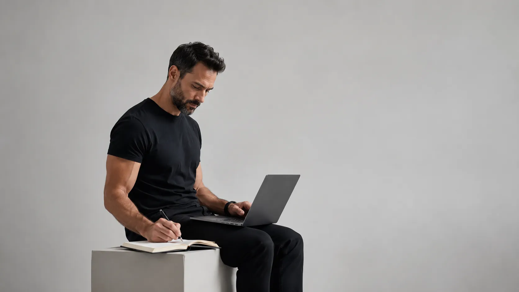 Homme assis sur un cube avec un laptop sur ses genoux et un carnet de note, il doit prende une sérieuse décision